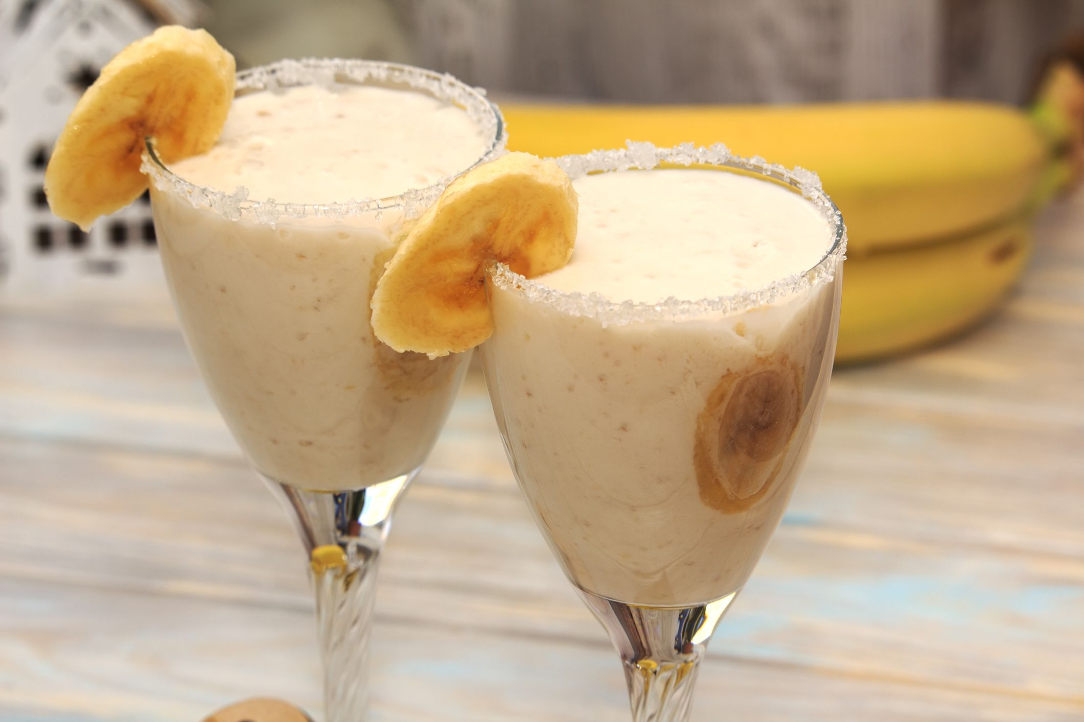 Homemade Banana smoothies on wood table in two glasses decorated with piece of banana