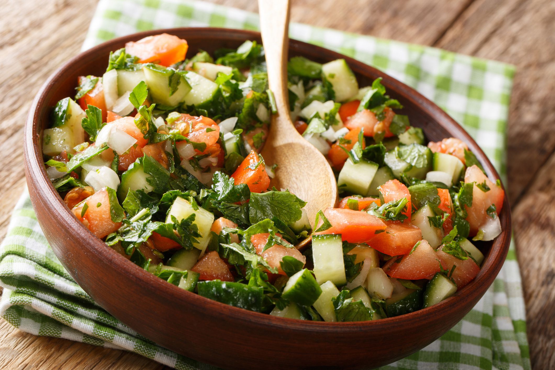 Shirazi salad of cucumbers, tomatoes, onions and herbs close-up in a bowl on the table. horizontal