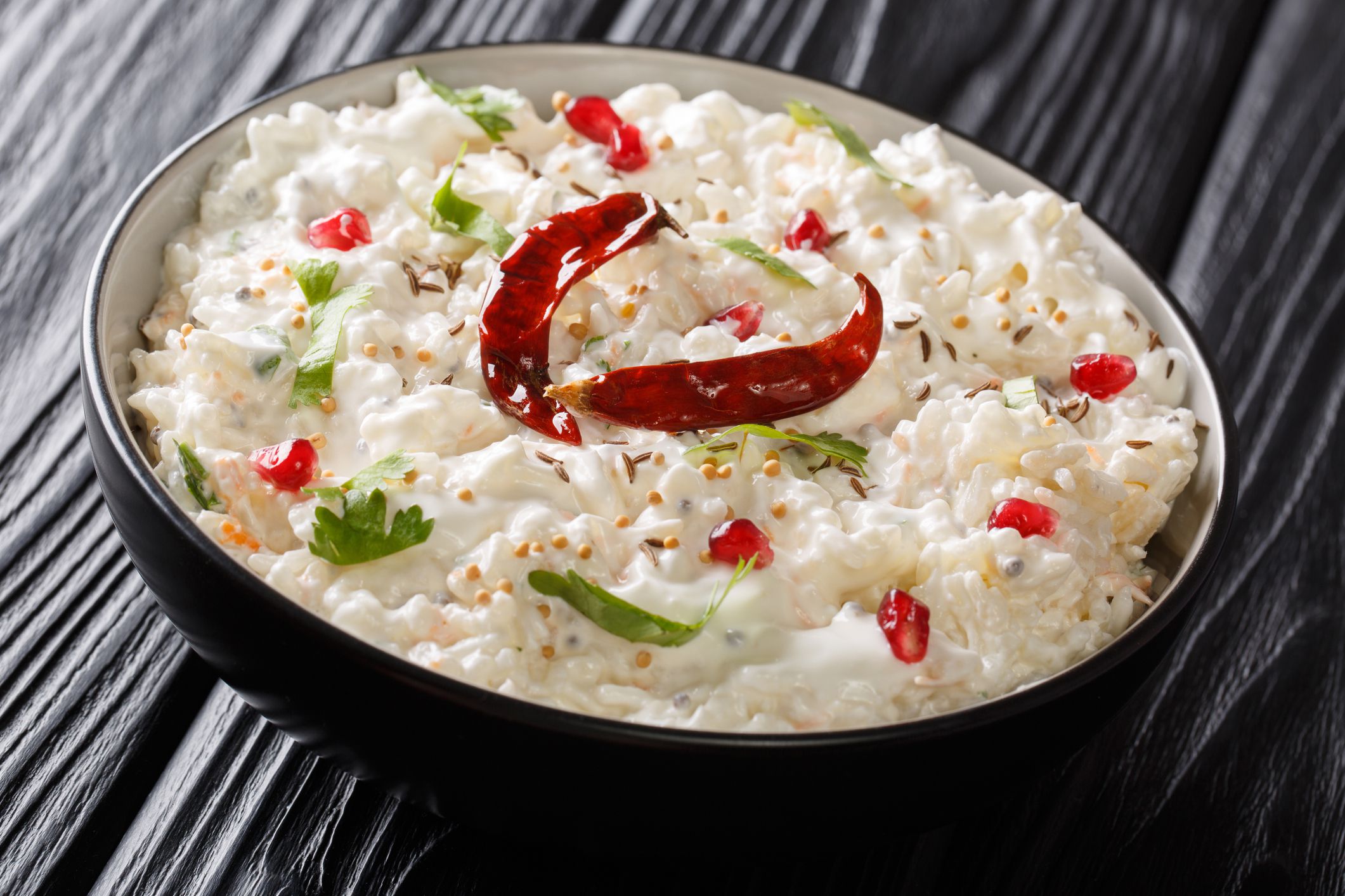 Indian Curd rice with carrots, pomegranate and with additional tempering of spices close-up in a plate on the table. horizontal