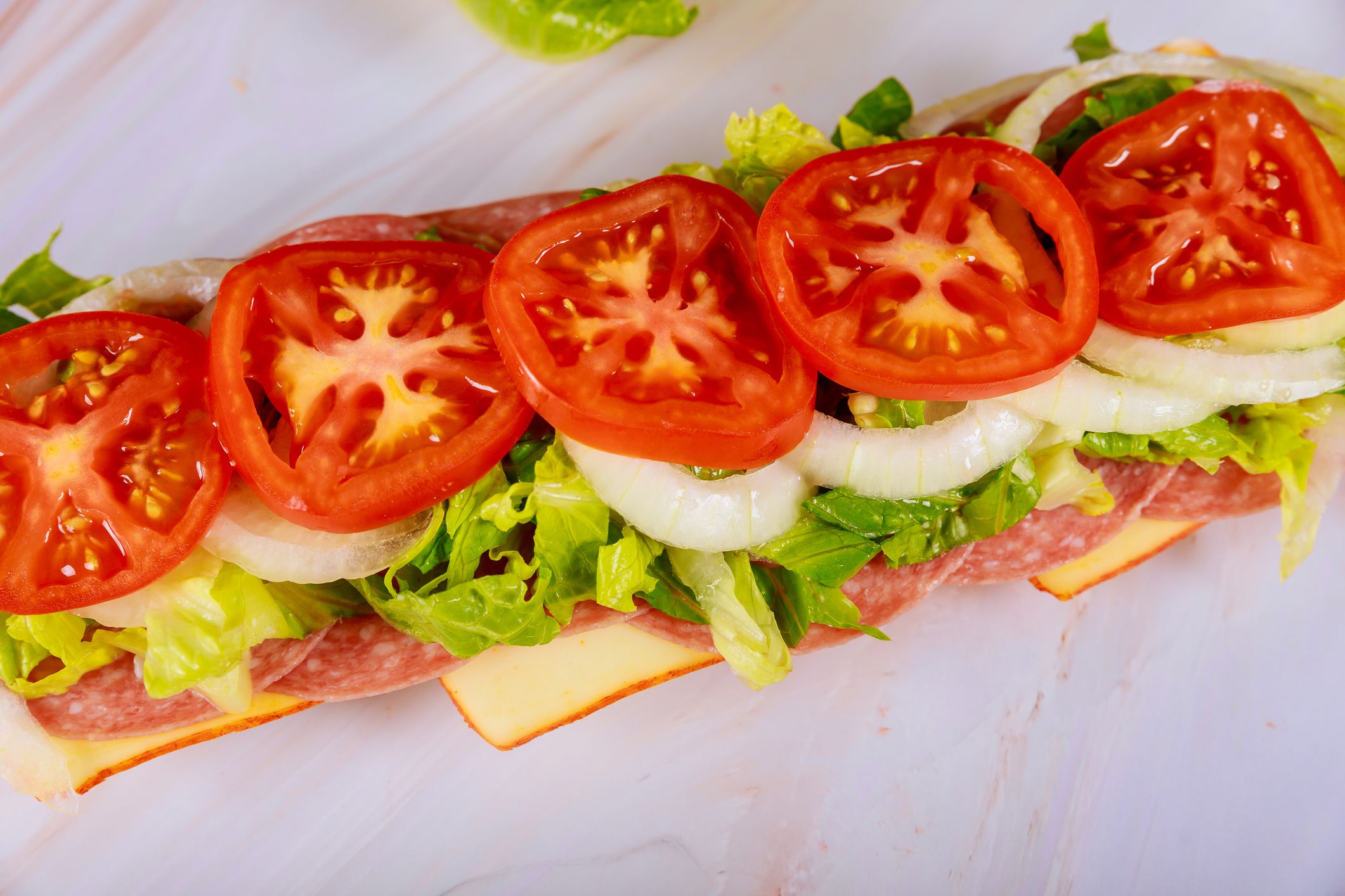 Long delicious sub with muenster cheese, salami, and vegetable.