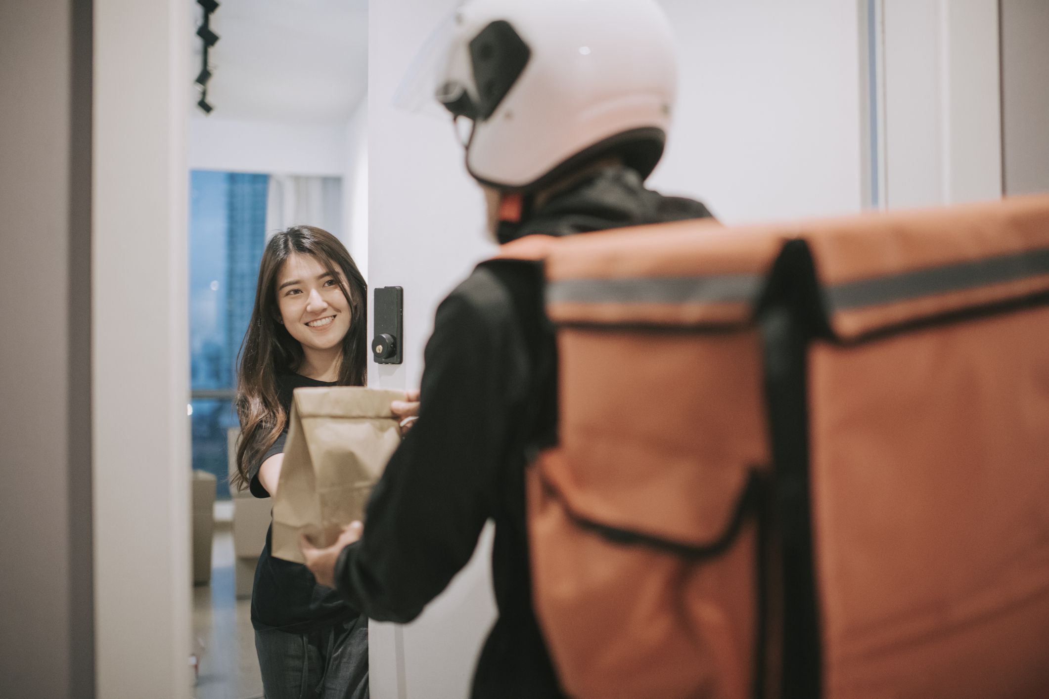 asian chinese delivery man with helmet press door bell for grocery food delivery