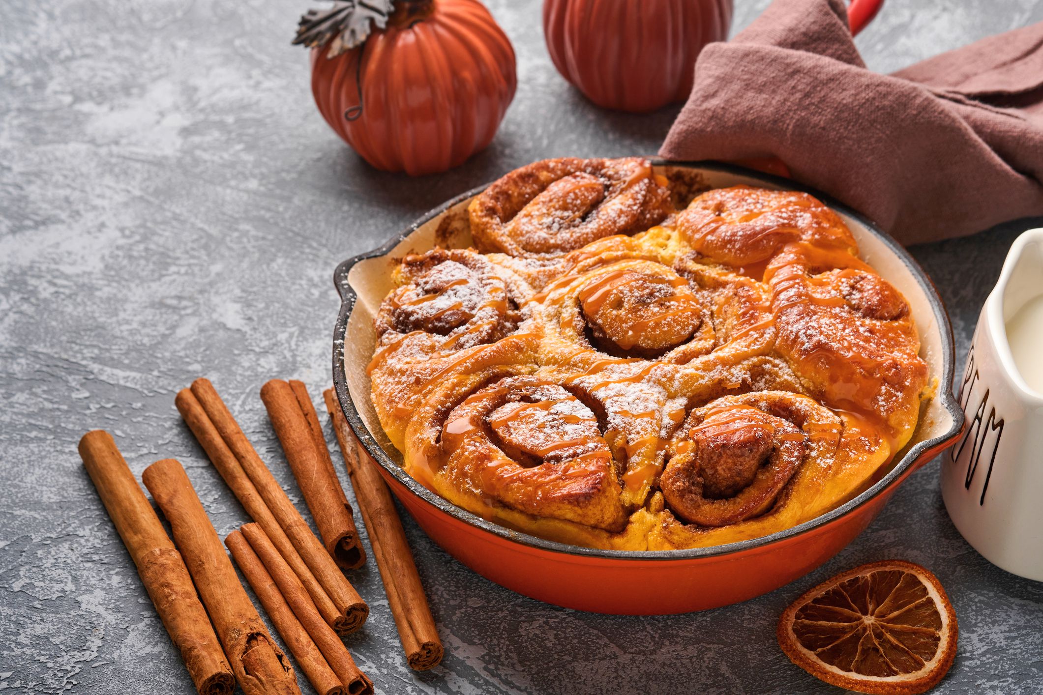 Cinnabon cinnamon rolls buns with pumpkin, nut, caramel and sugar cream iced. Top view. Sweet Homemade Pastry christmas baking. Close-up. Kanelbule - swedish dessert.