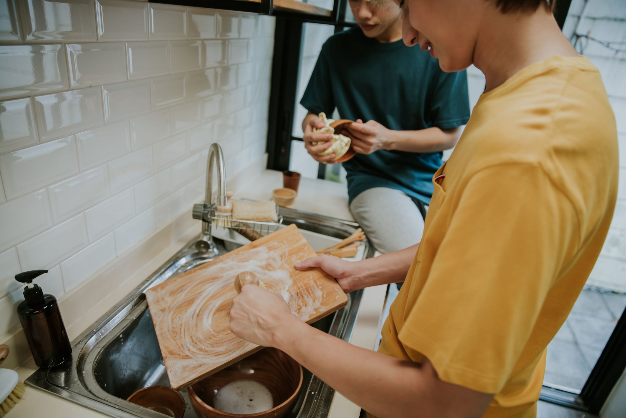 Southeast Asian Gay person Washing Up At Home Using Eco Dish Brush For Sustainable Lifestyle