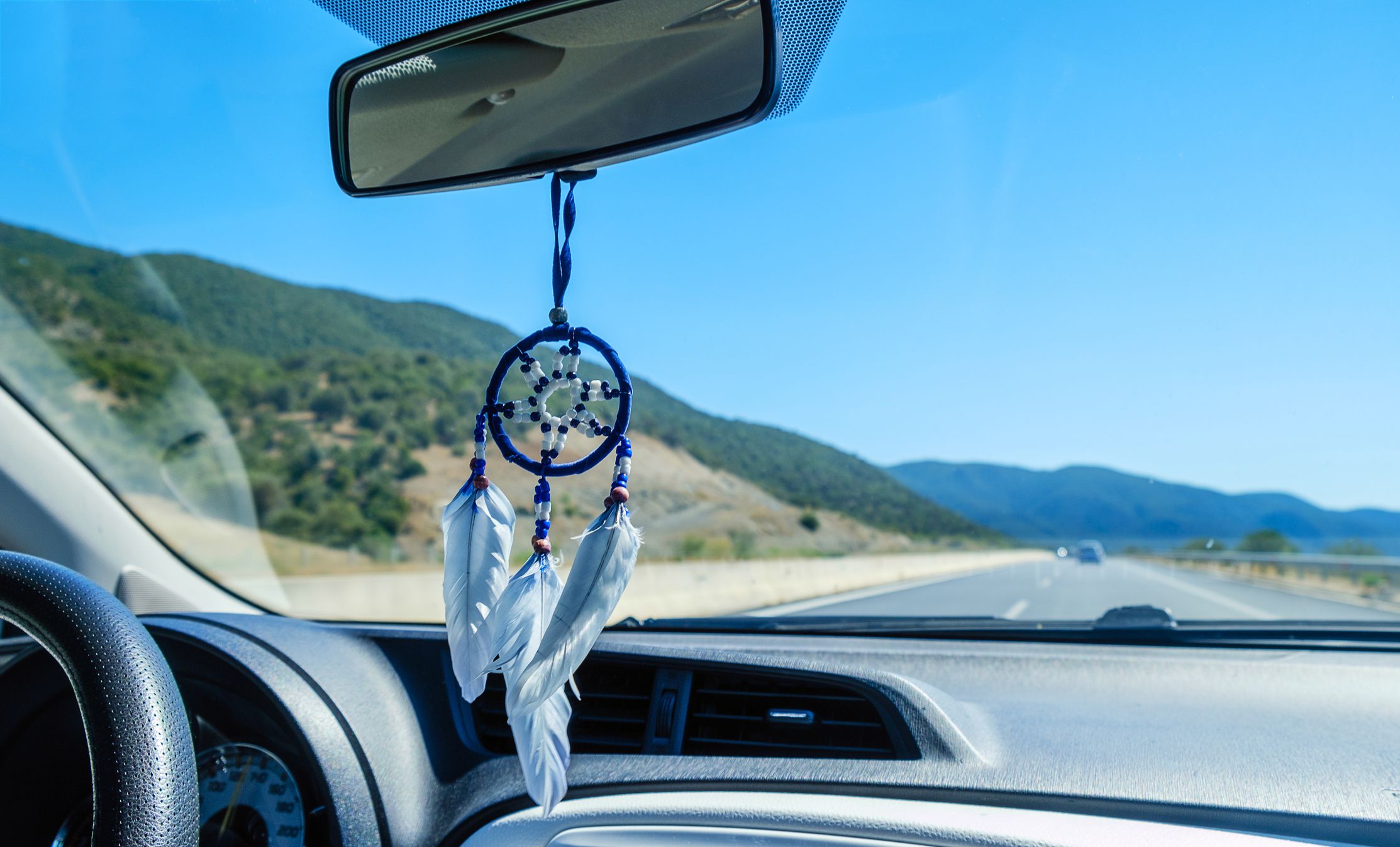 Dream catcher hanging inside car on a windshield. Road trip