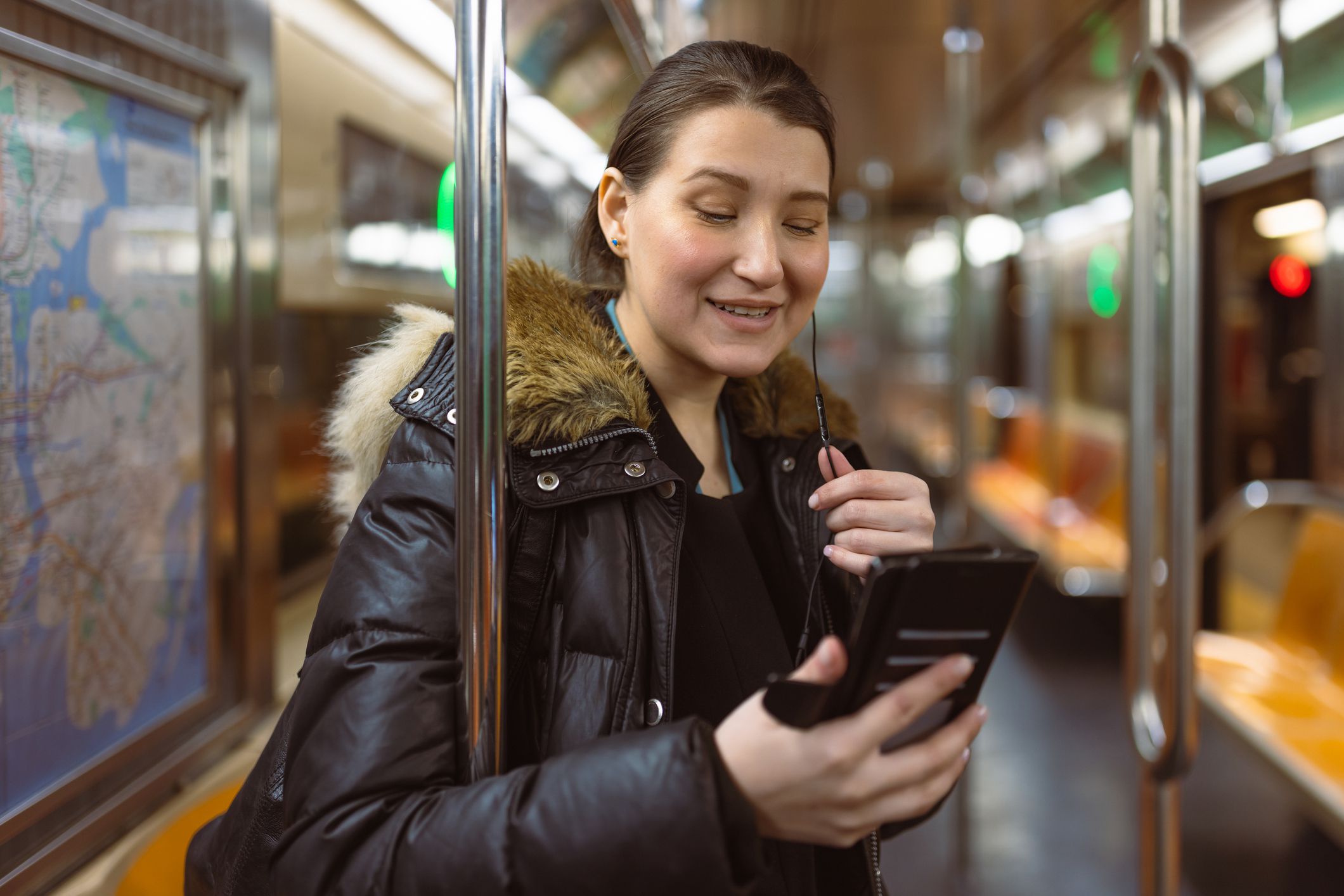 Hispano-latin businesswoman in a NYC subway, heading home after work. She is having a video call. Downtown Manhattan, New York, USA