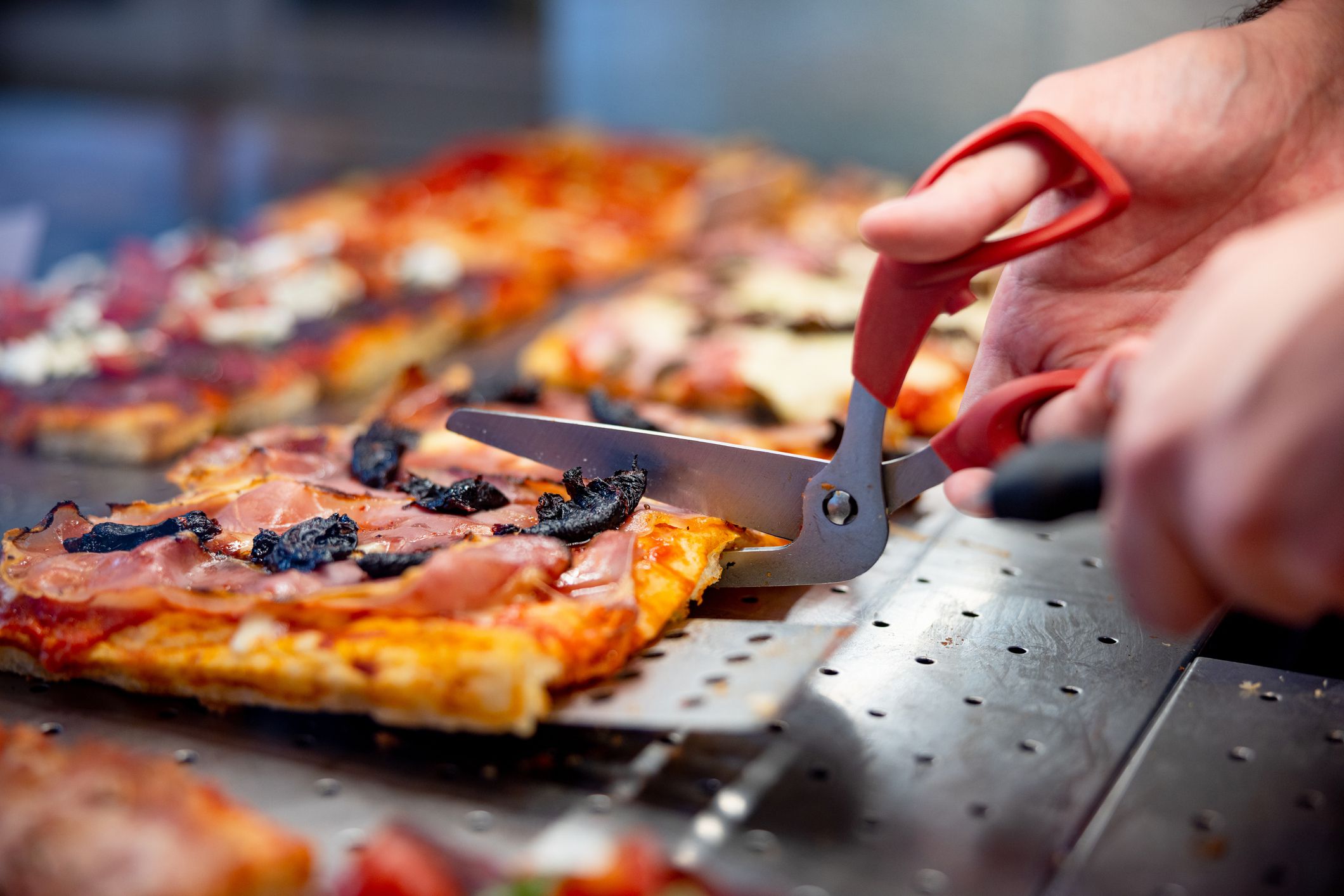 Pizza al taglio served in take out, cutting pieces in rectangular shape with special scissors and served with spatula