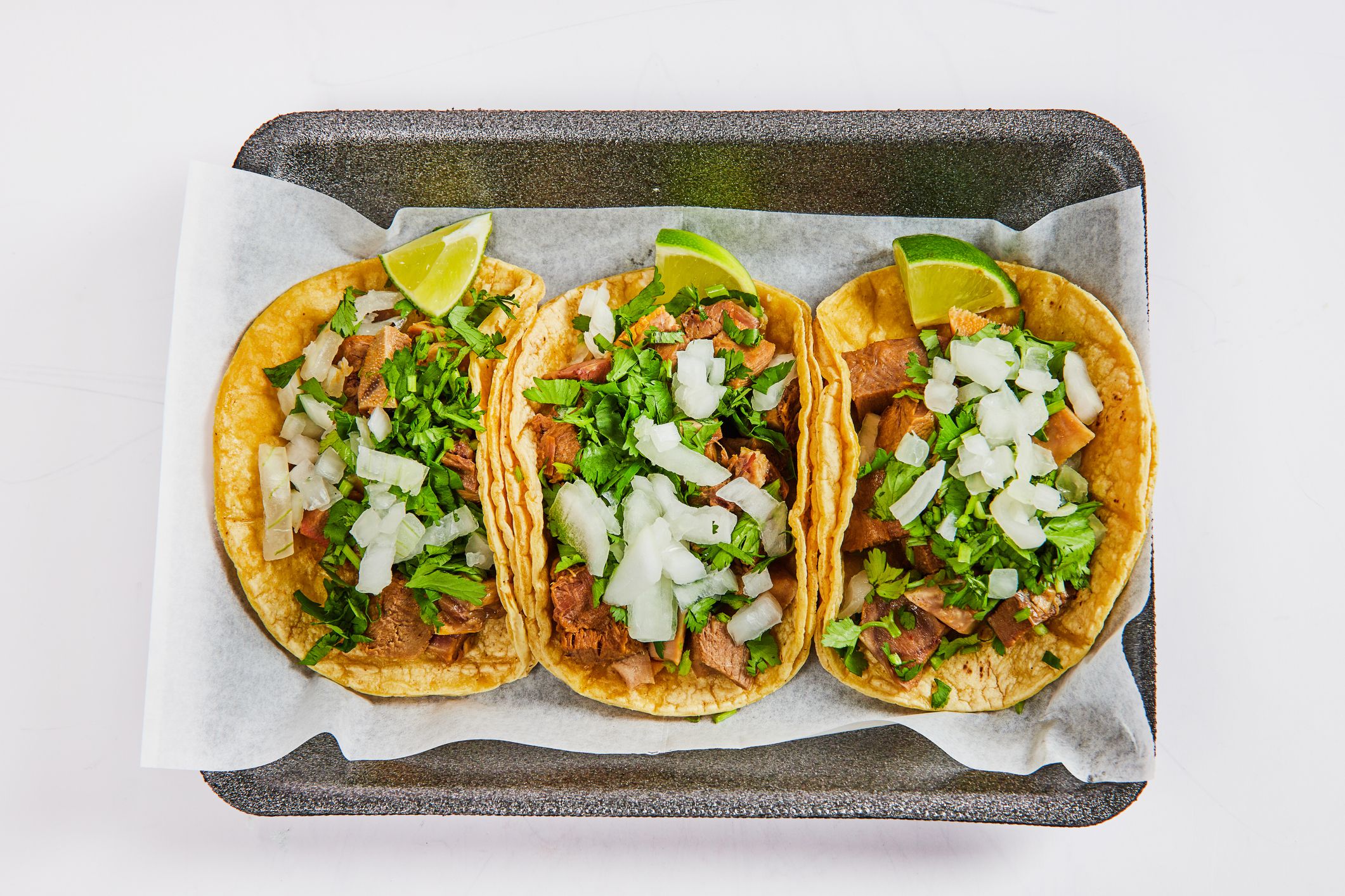 Image of Asset three lengua cow tongue street tacos with lime wedges