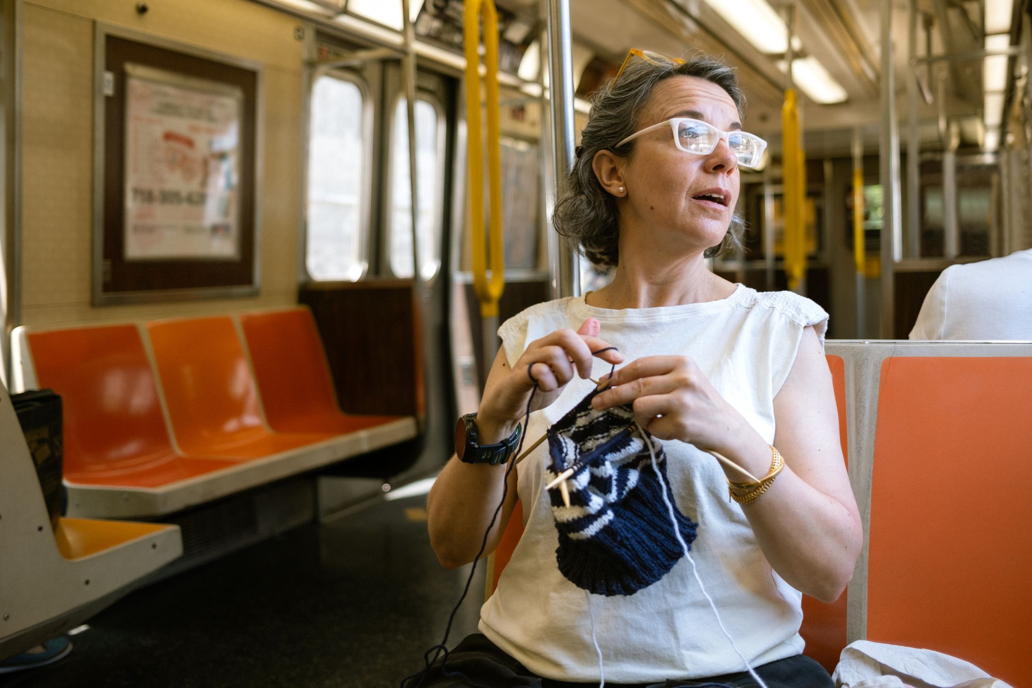 Mature woman knitting during subway commute in New York City