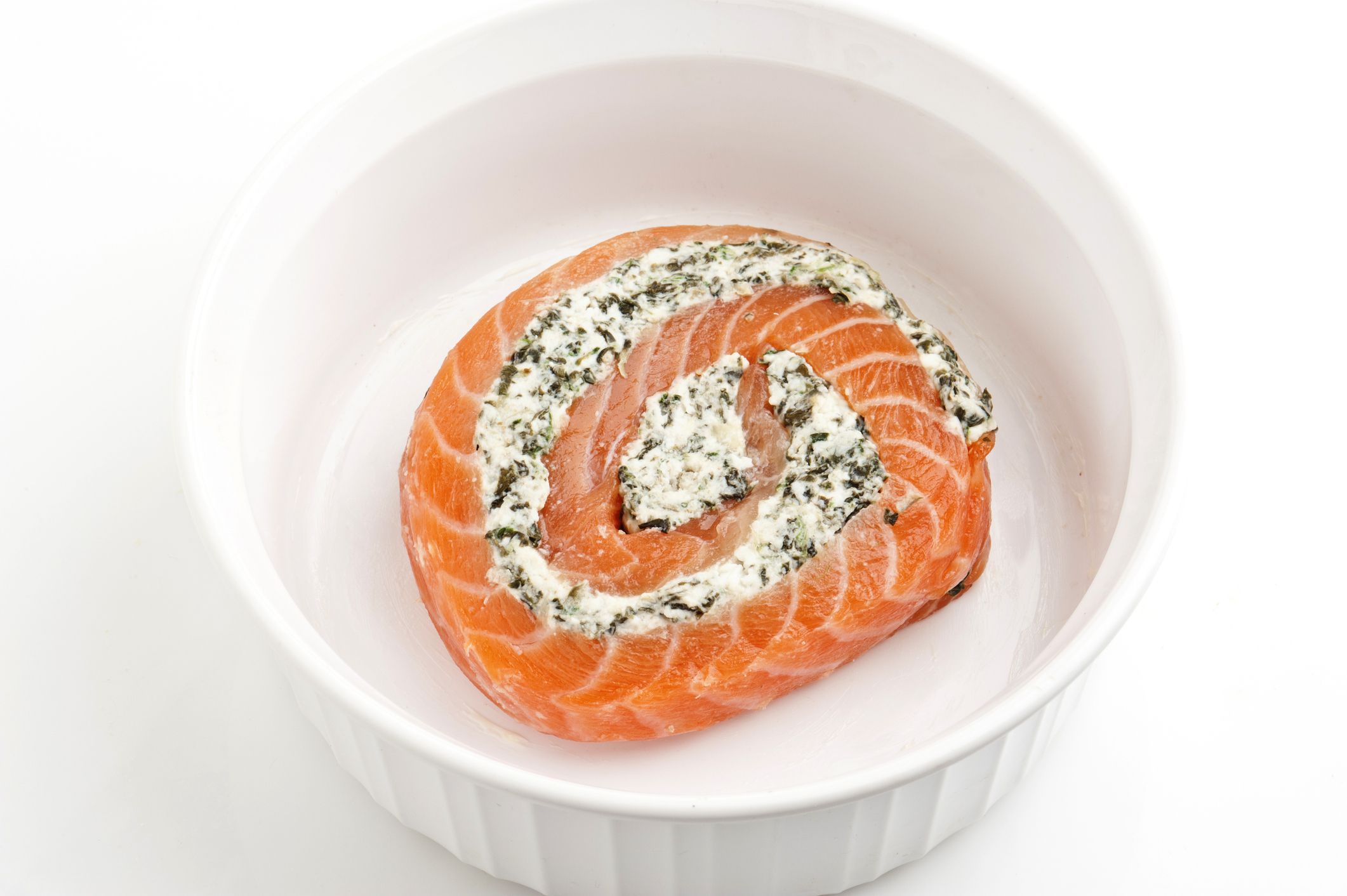 Spinach and feta Salmon Pinwheel in a caserole on white background
