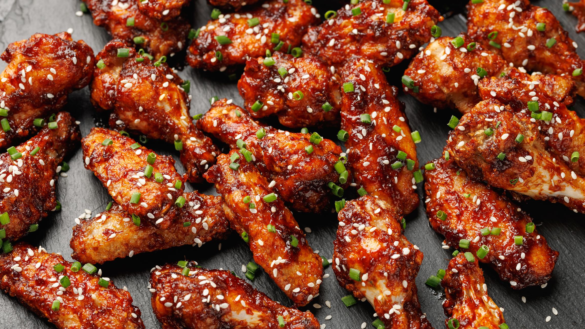 Spicy korean chicken wings with sesame seeds and chives.