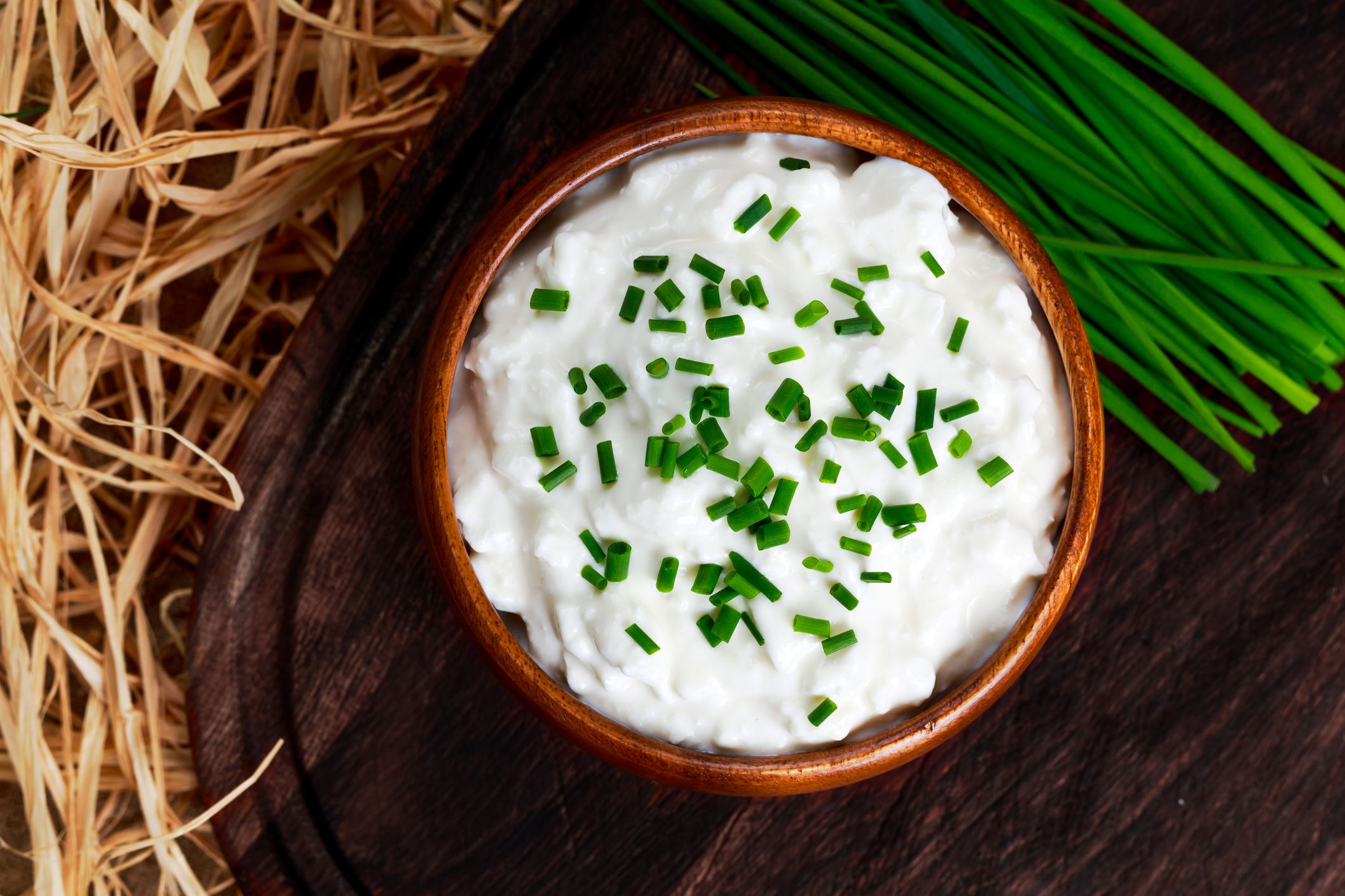 Cottage cheese with chives in wooden bowl
