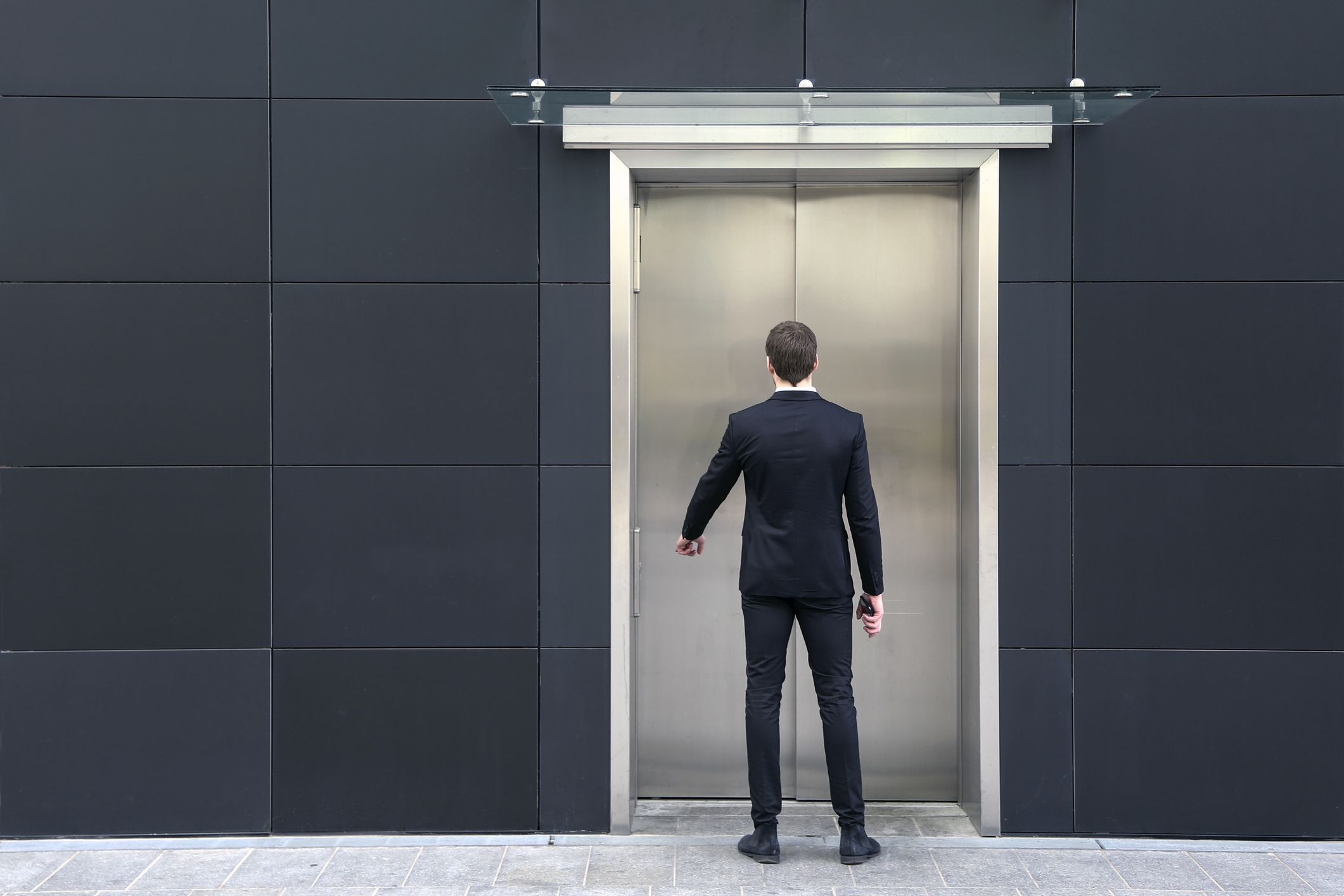 Rear view of an unrecognizable Caucasian male businessman using elevator.