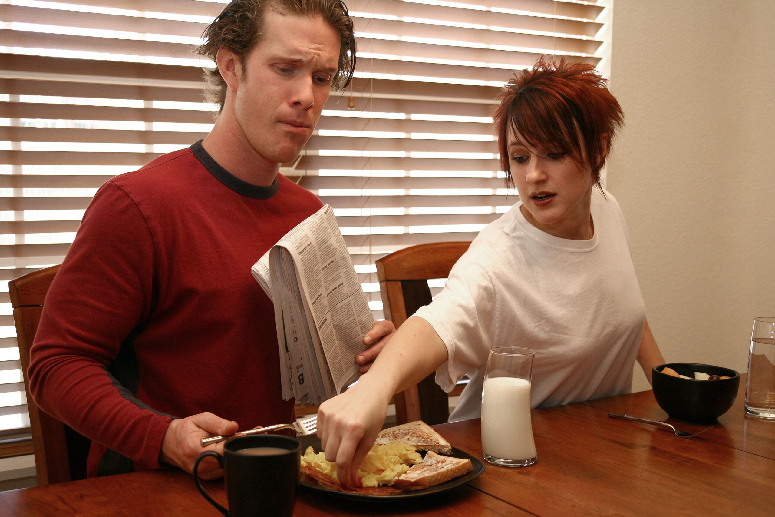 Woman stealing man's breakfast. Attractive thirties couple.