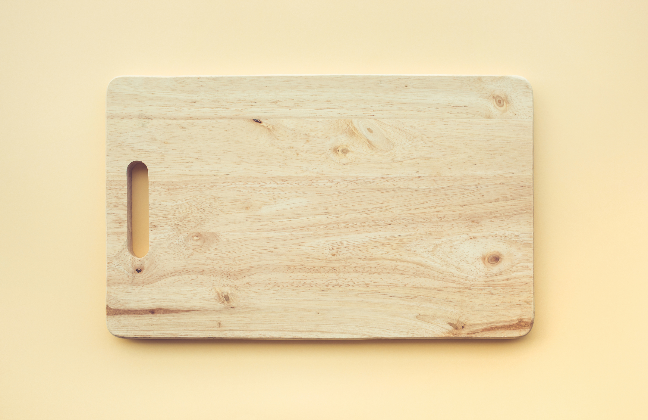 Wooden Cutting Board on a Light Yellow Background