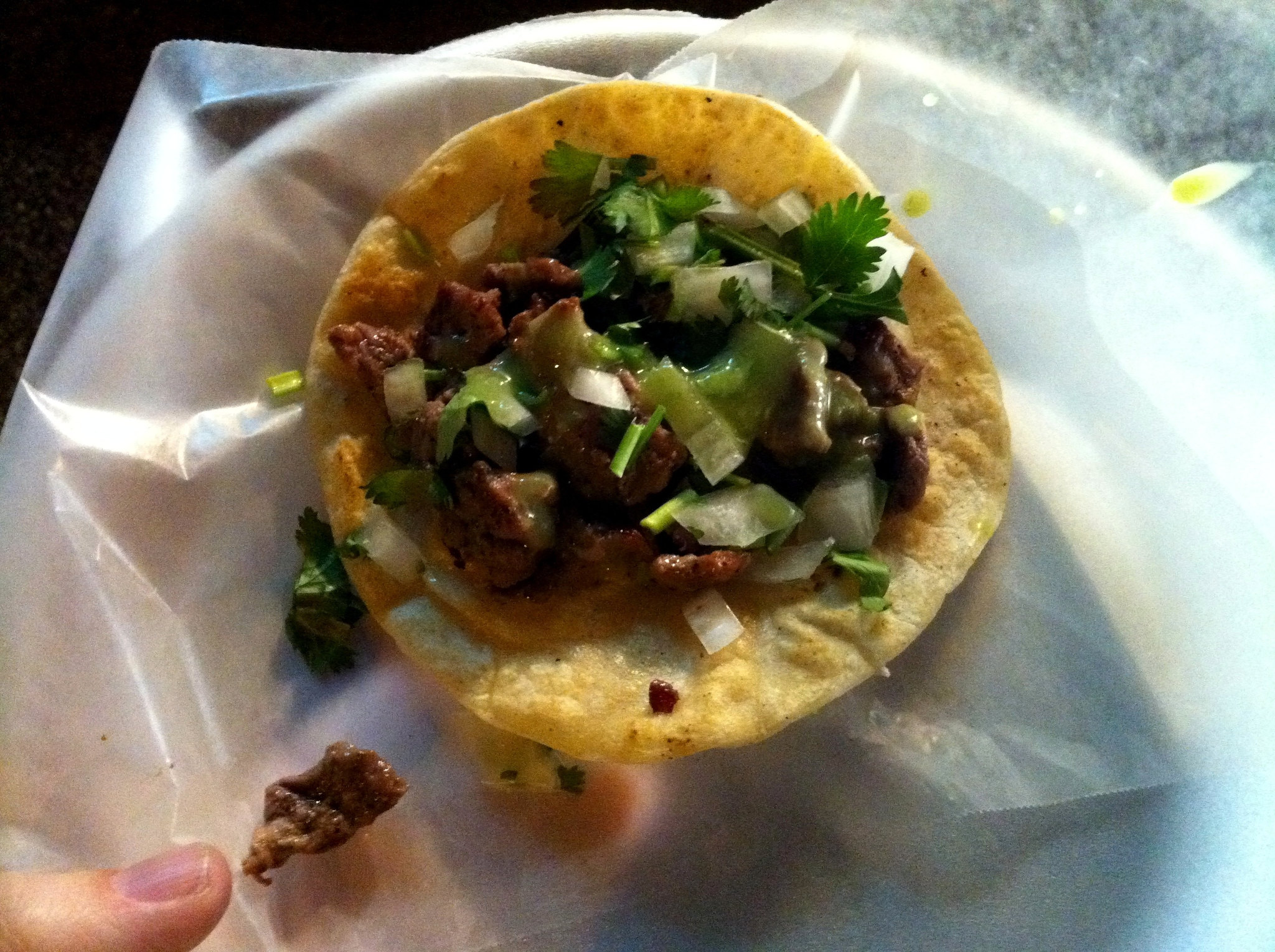 A Taco on Wax Paper, Held by a Finger