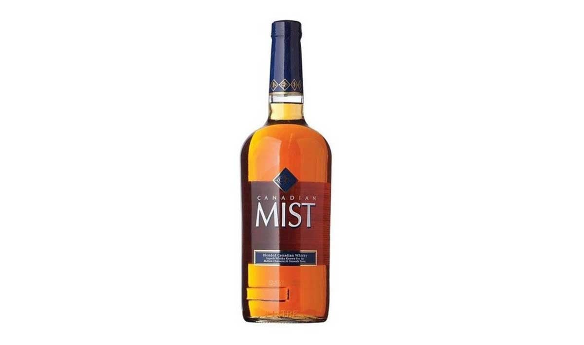 A bottle of Canadian Mist whisky, often listed among the worst whiskeys, with a blue cap and label, filled with amber-colored liquid, standing upright on a white background.