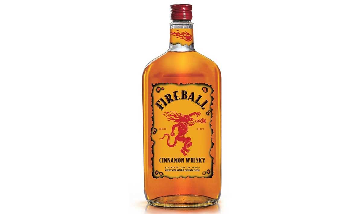 A bottle of Fireball Cinnamon Whisky, often listed among the worst whiskeys, features a yellow label, red cap, and a fiery red dragon logo in the center. The text on the label reads "Fireball Cinnamon Whisky.