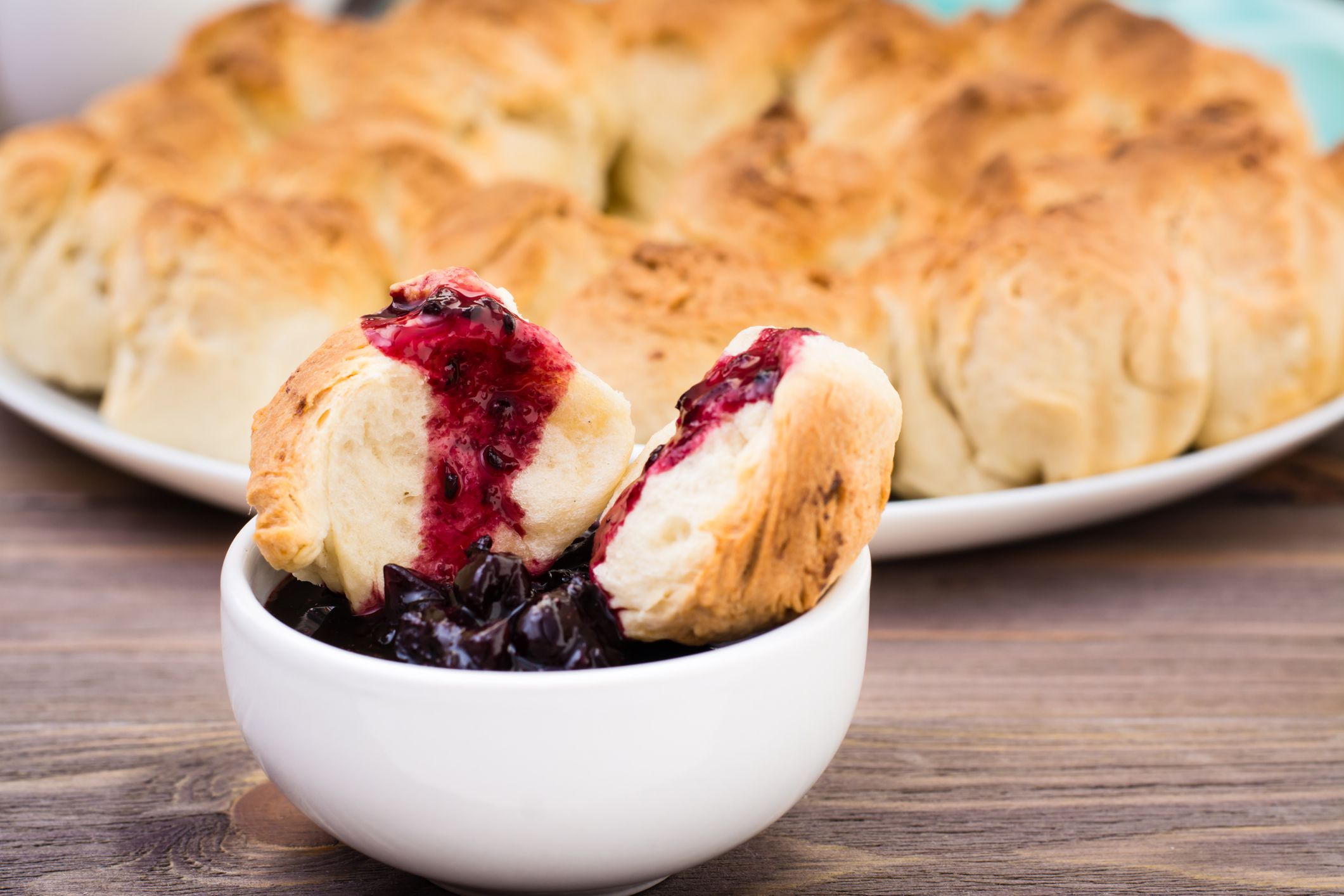 Pull apart monkey bread with black currant jam in a plate on a wooden plate