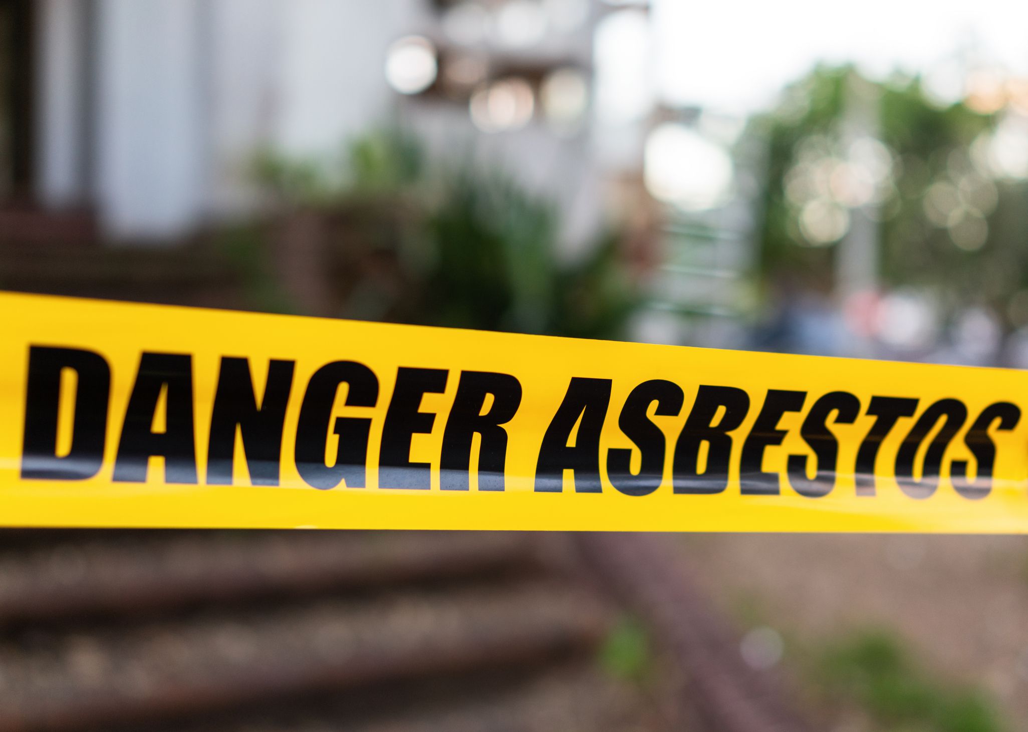 Yellow cordon tape warning of asbestos danger at the entrance to a house being renovated.