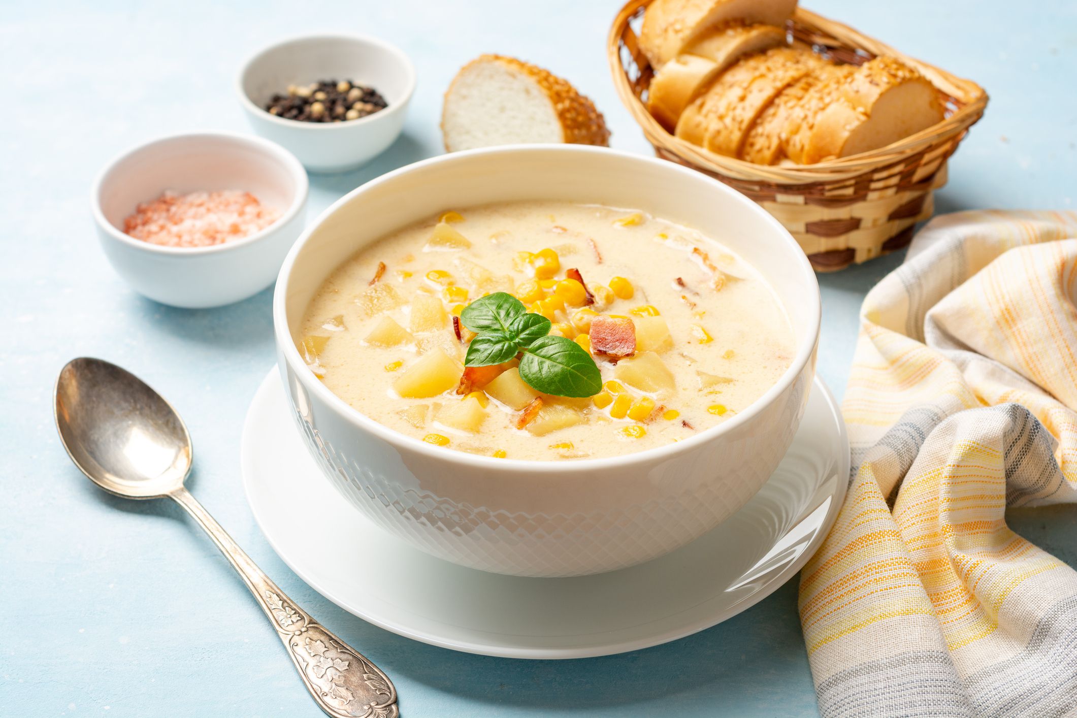 Corn chowder soup in white bowl on concrete background. Selective focus.
