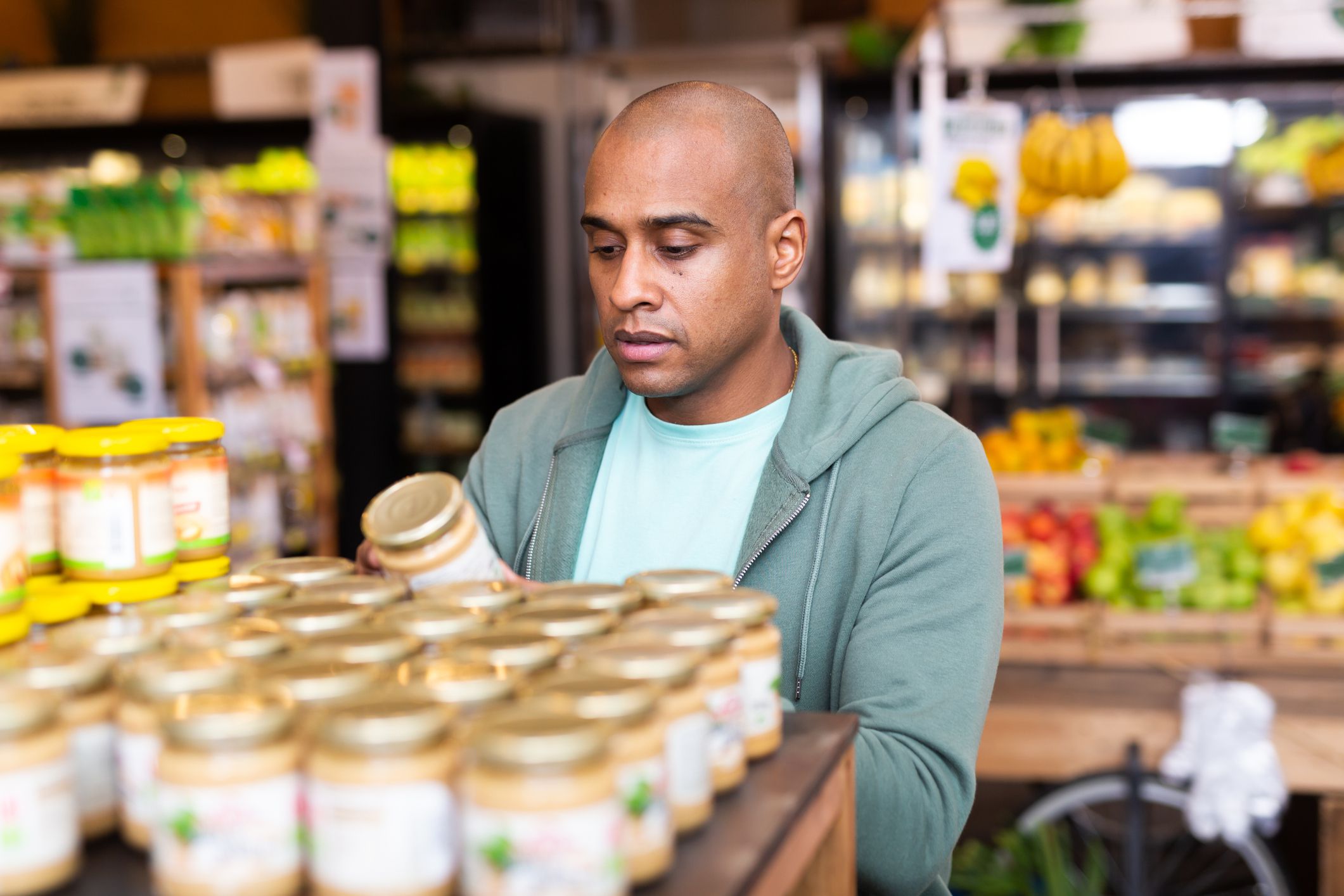Latin american man reading jar contents on label while shopping in food department of supermarket