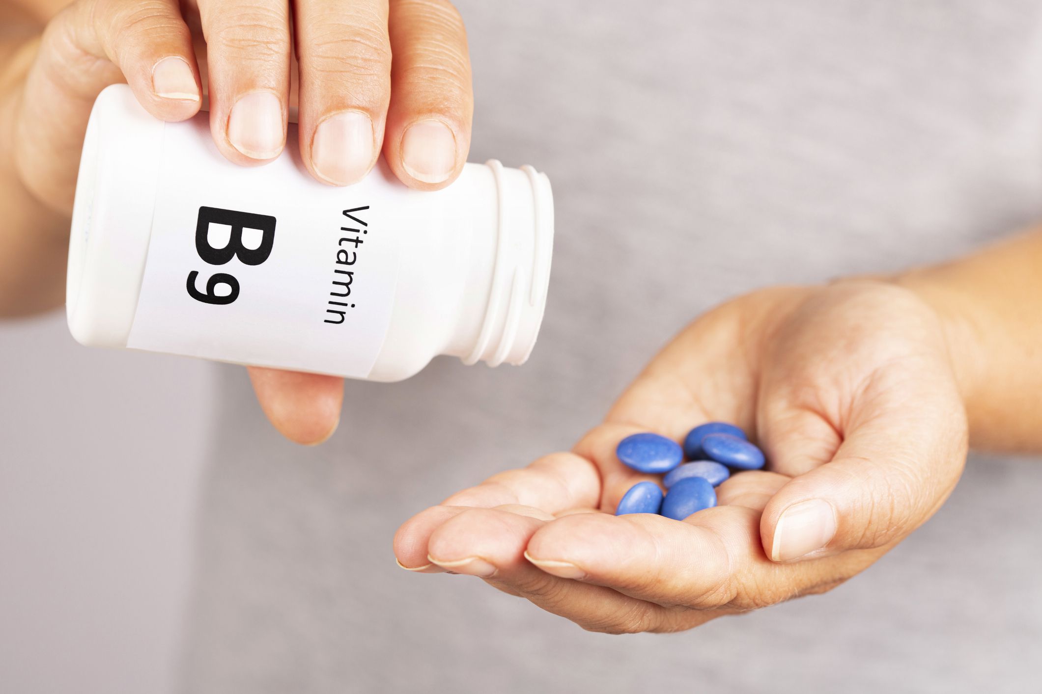Woman hand takes vitamin B9 from medicine container