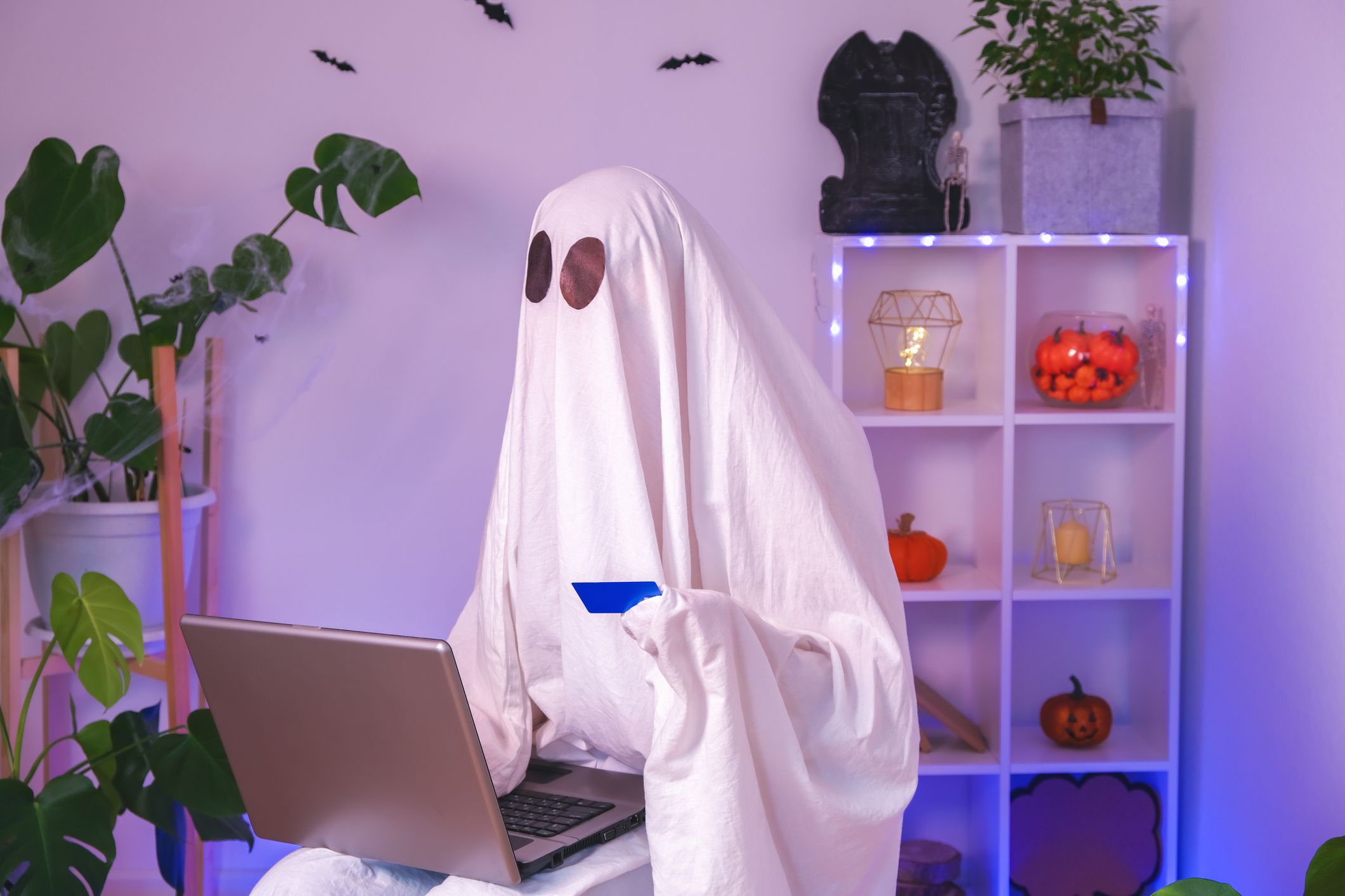 The ghost of Halloween uses laptop to surf the Internet, to browse online stores, markets. A ghost makes an order from computer for Halloween. Ghost pays for online purchase by credit card, bank card