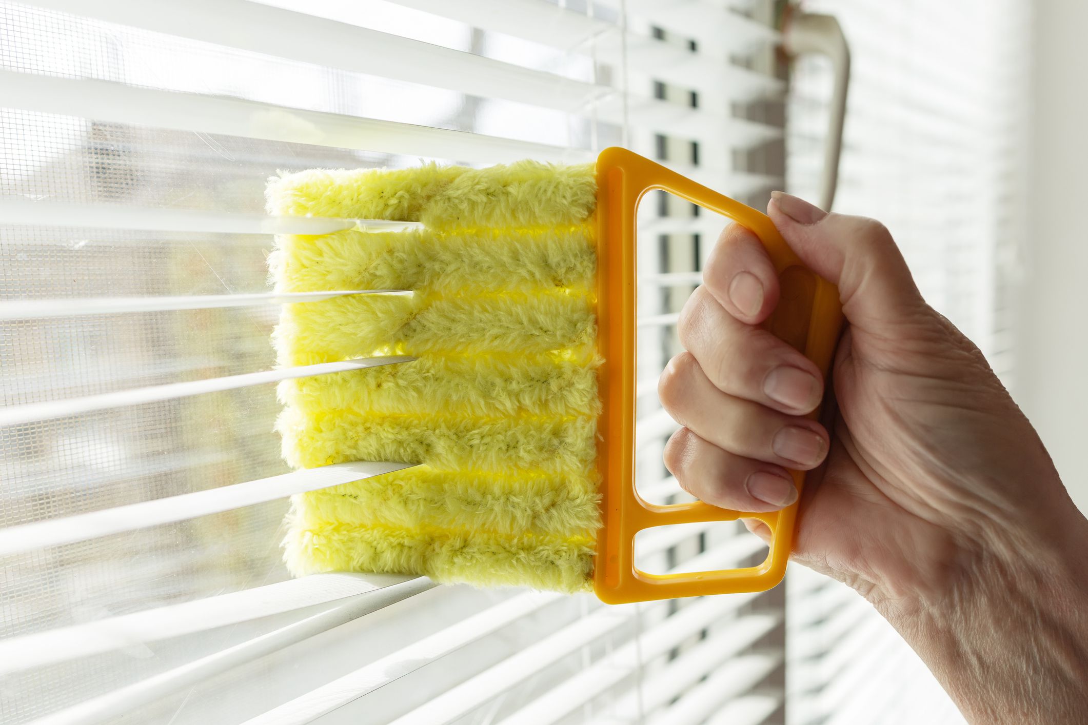 Woman cleaning window blinds with rag indoors, closeup,