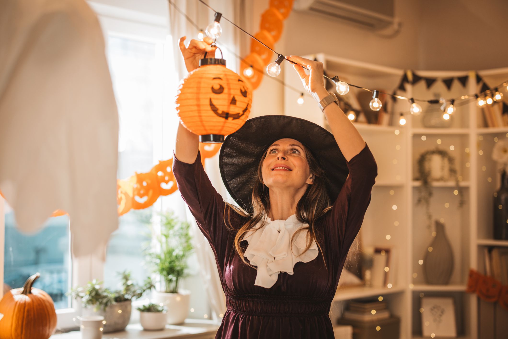 Mature woman in costume decorating home for Halloween, everything need to be perfect when family gather around.