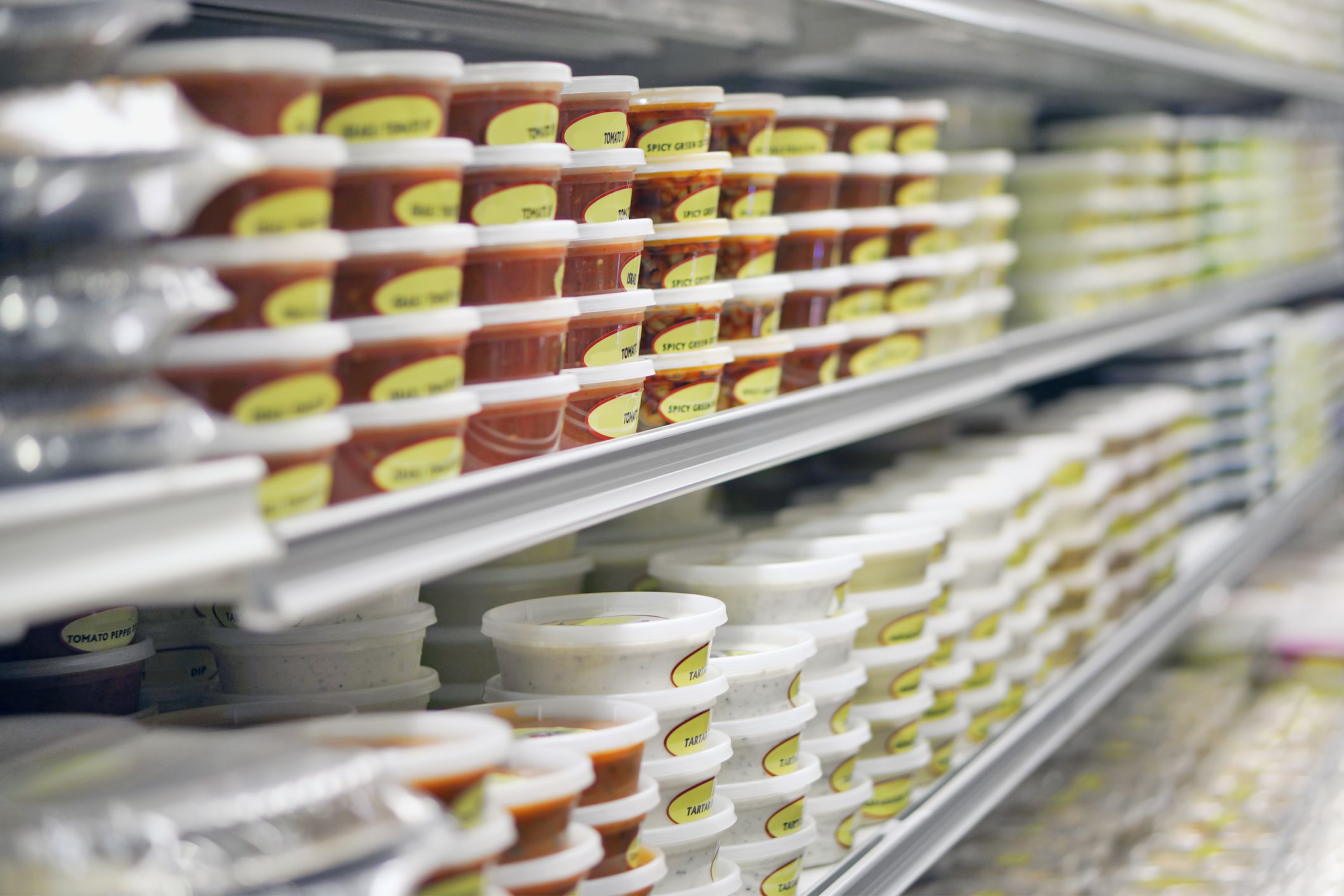 Dips on refrigerated takeout store shelves. Labels are generic, unbranded descriptive of contents such as