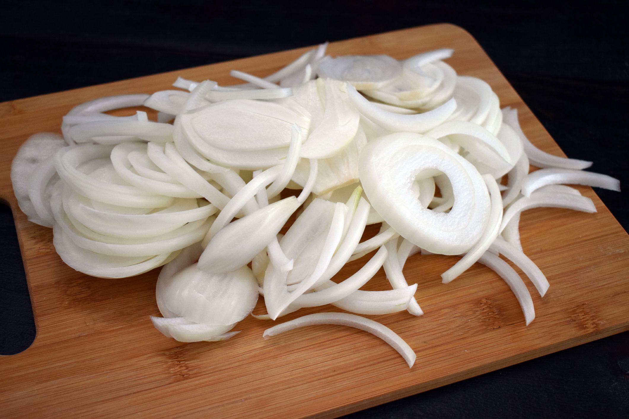Sliced onions on a bamboo cutting board