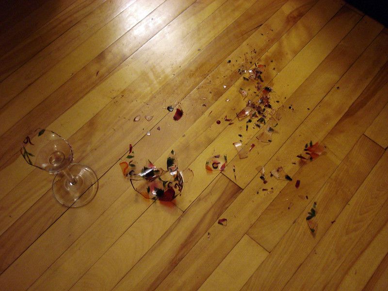 pieces of broken glass from a wine glass on a hard wood floor