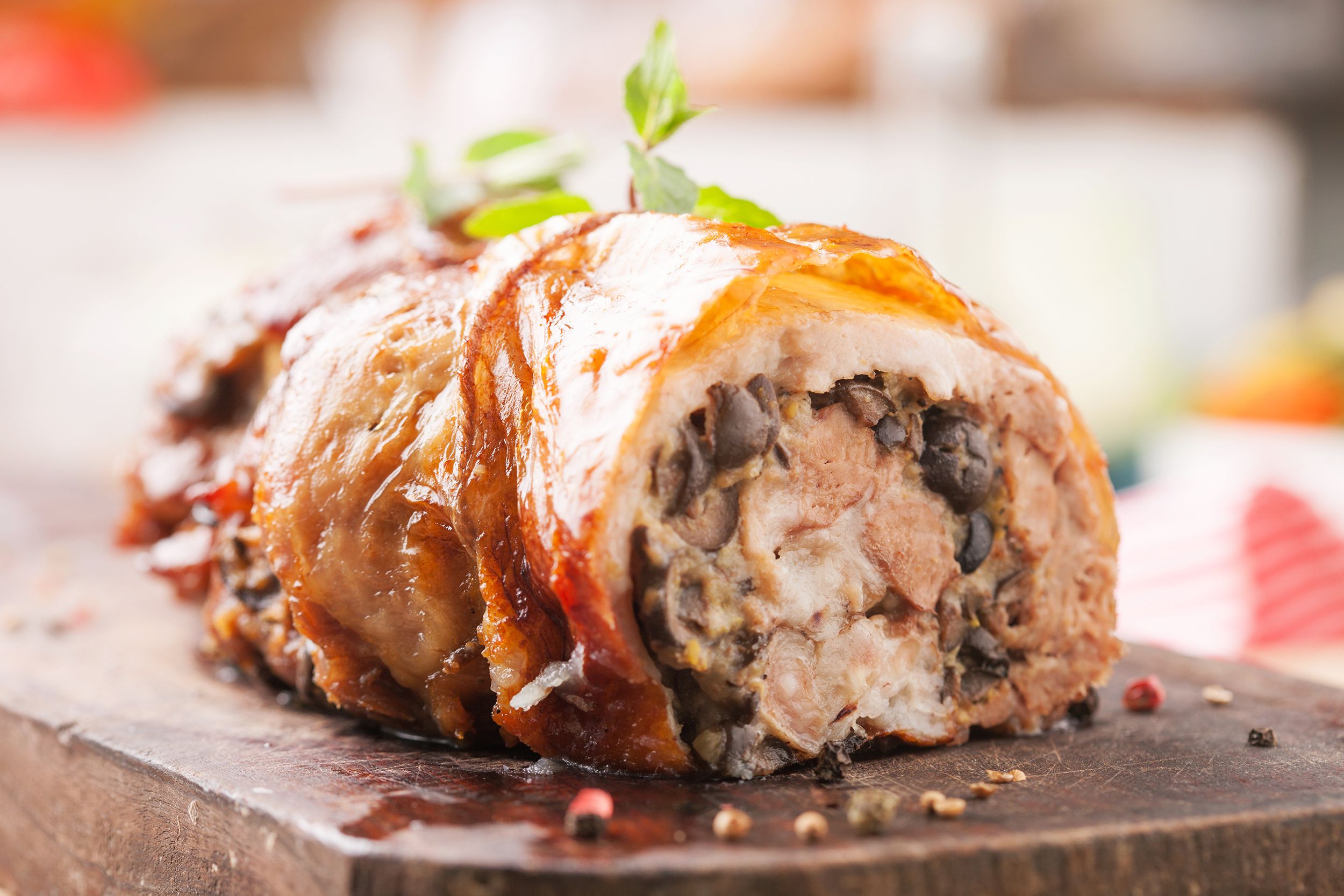 Closeup of stuffed pork tenderloins with bacon and apple-riesling sauce on a wooden cutting board with a blurred background