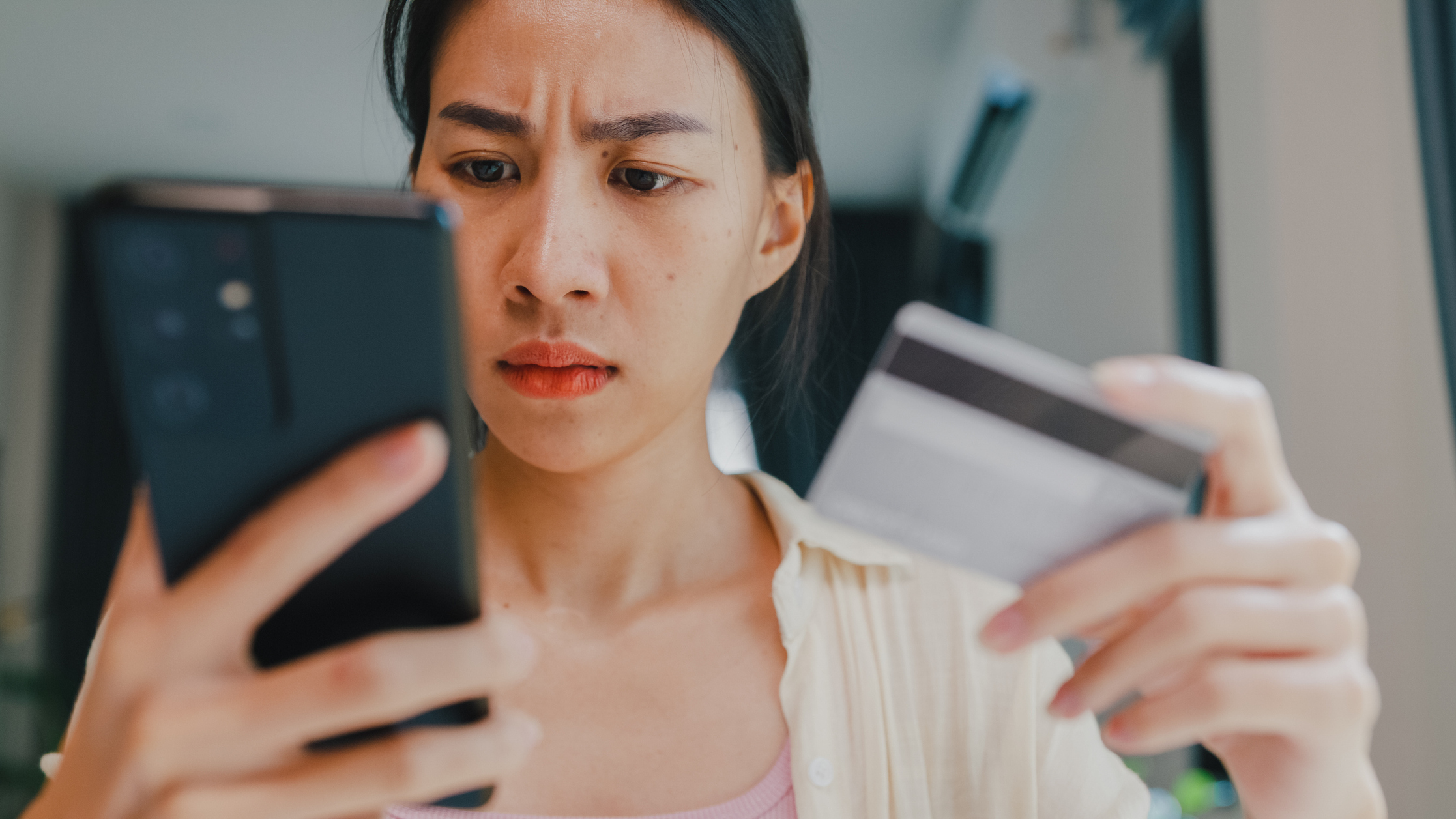 Closeup of Worried Woman on Smartphone With Credit Card