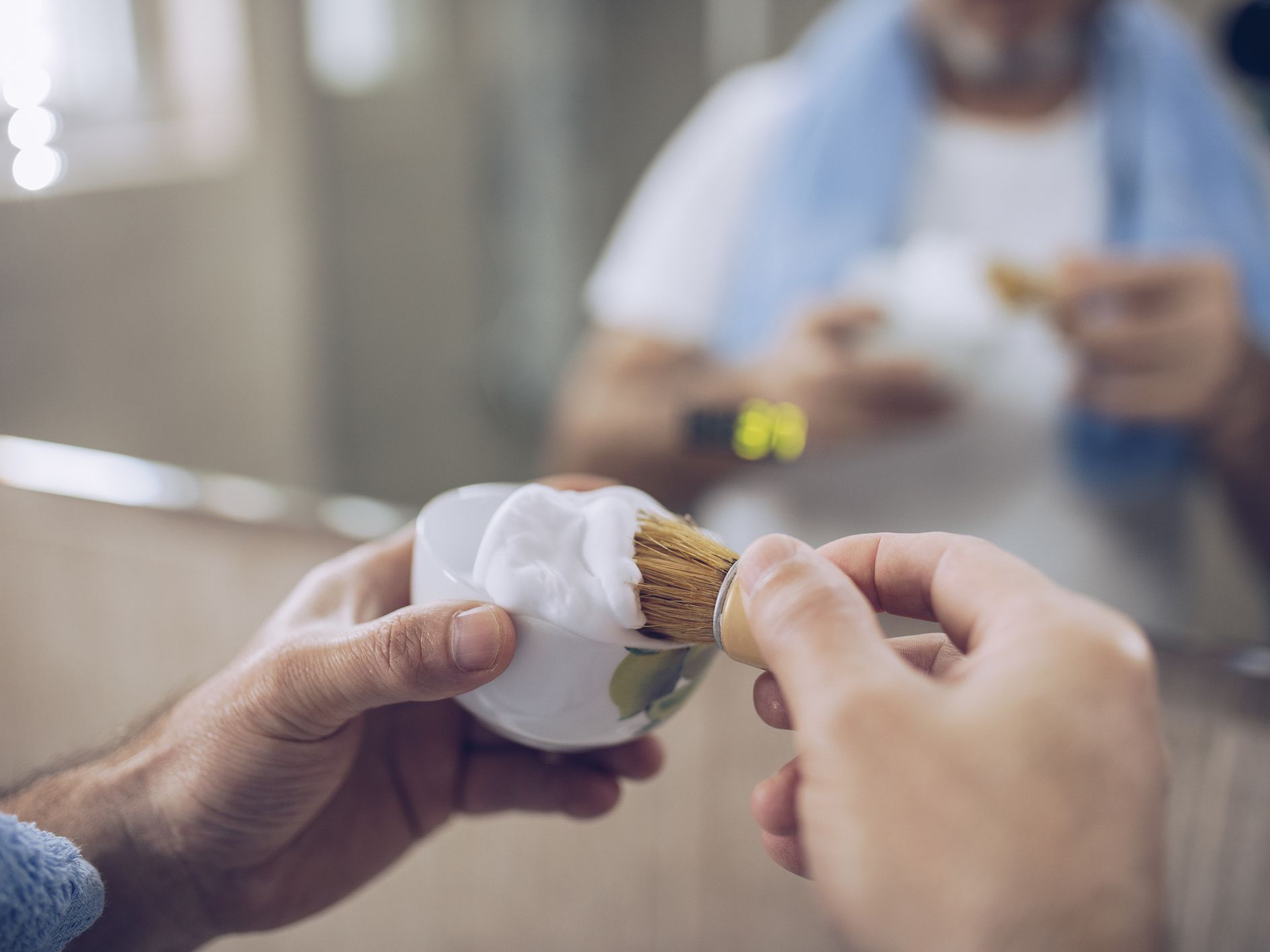 An older man shaves, preparing for work