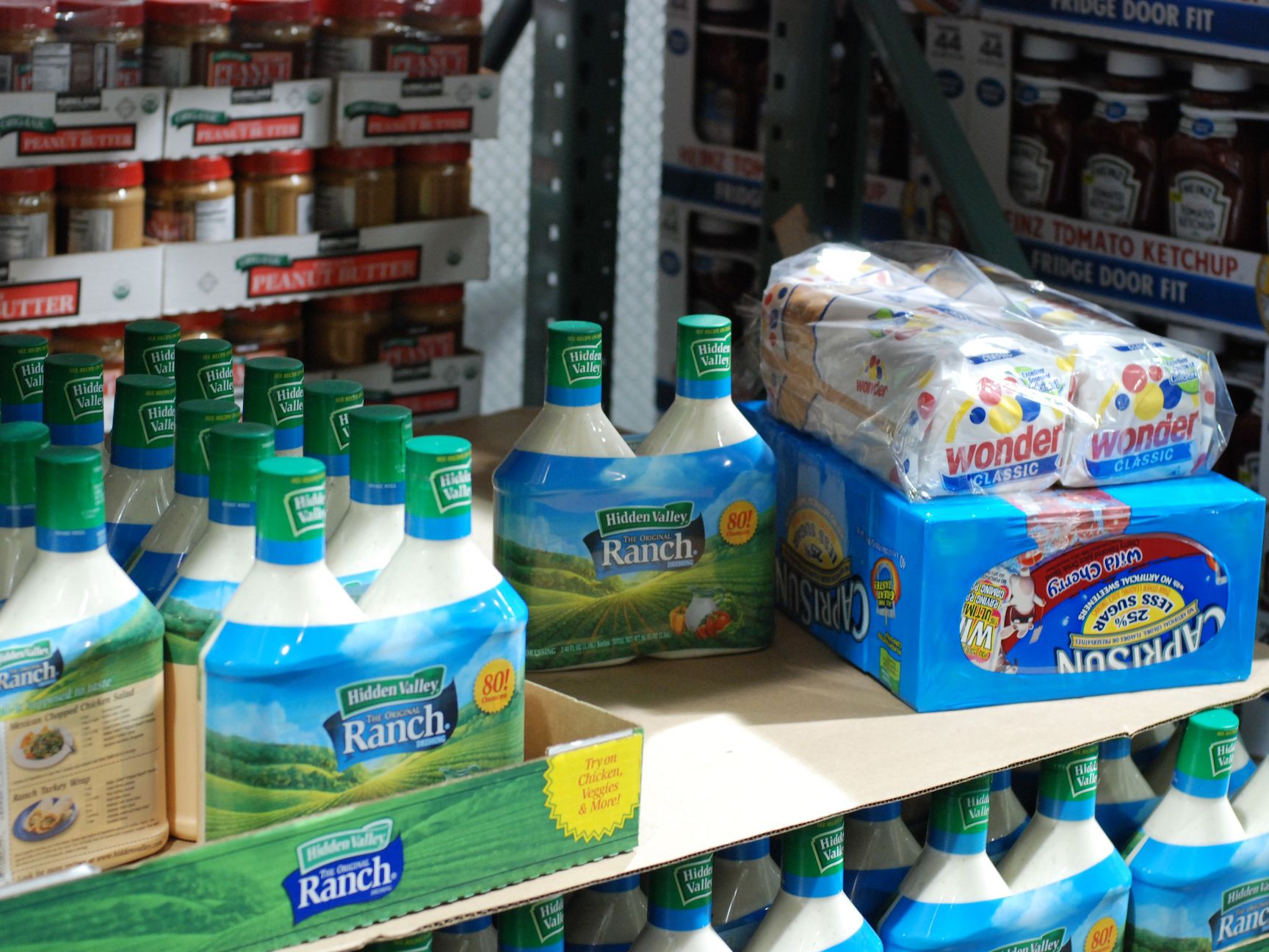 Bottles of Hidden Valley Ranch dressing and packages of Wonder Classic White bread are displayed on a store shelf, with jars of peanut butter and ketchup visible in the background.