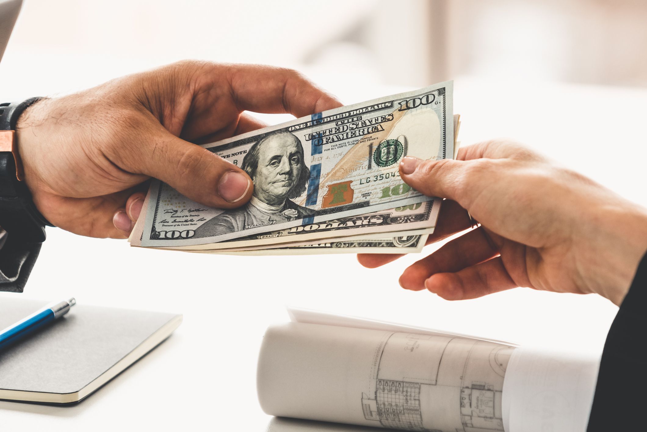 Businessman hand sending money to another business person. Transaction, payment, salary and banking concept.