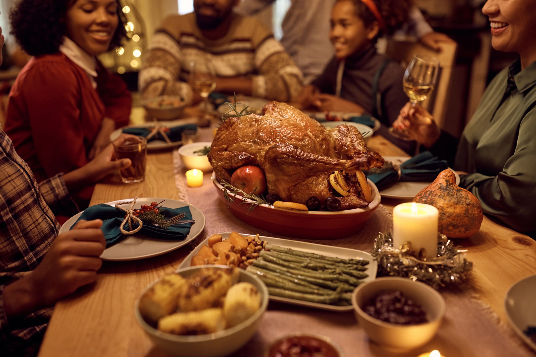 Close up of African American family gathering for Thanksgiving dinner at dining table. Focus is on roast turkey.