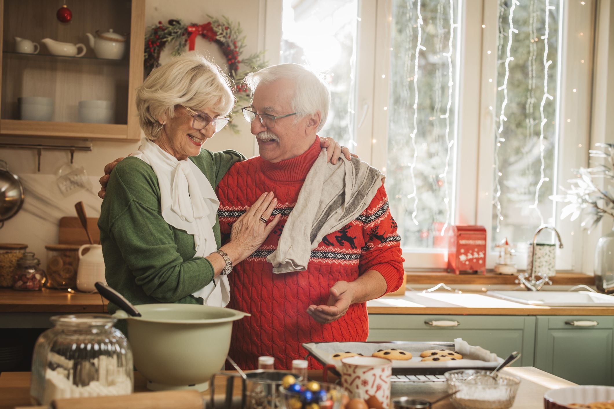 Senior couple having fun while baking cookies for Christmas in kitchen