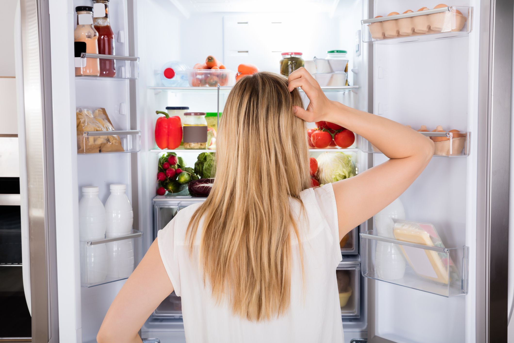 Rear View Of Young Woman Looking In Fridge At Kitchen