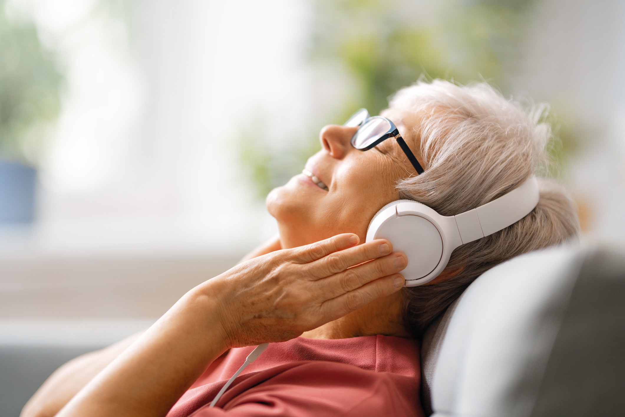 Side-View of Senior Woman Laying in Chair Listening With Headphones on to Music, Selective Focus