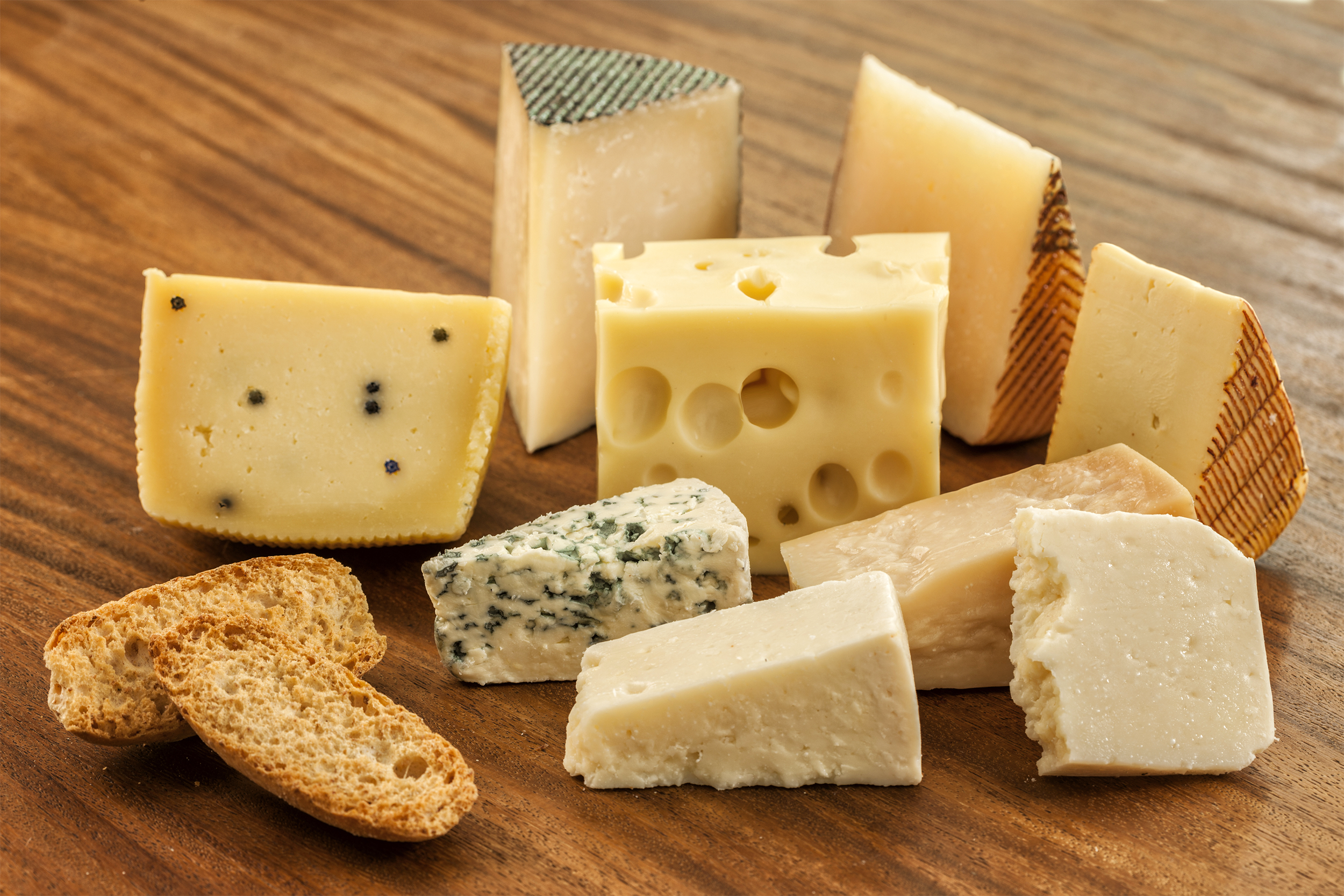 Assorted cheeses, emmental, blue cheese, pecorino, parmesan and manchego among other matured cheeses, on a wooden table