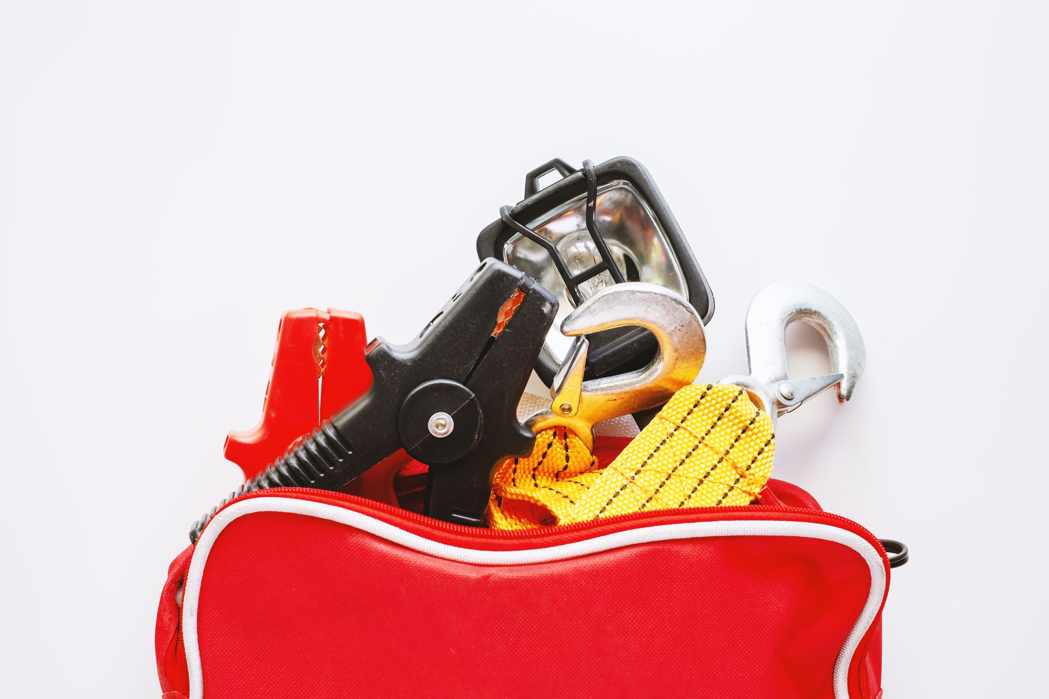 Car emergency kit items spilling out in a red bag on a white background