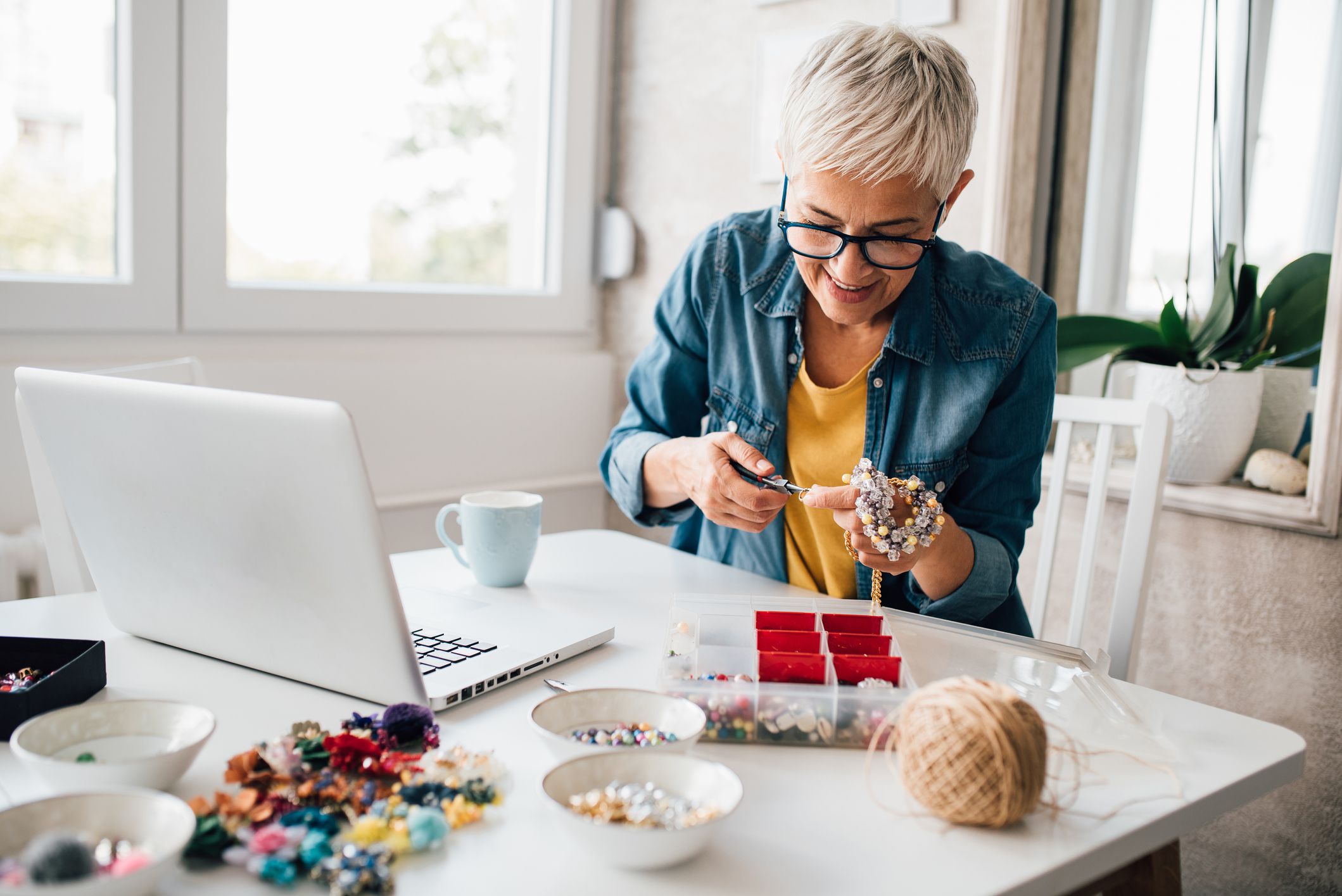 Mature woman watching online tutorials for making jewelry.