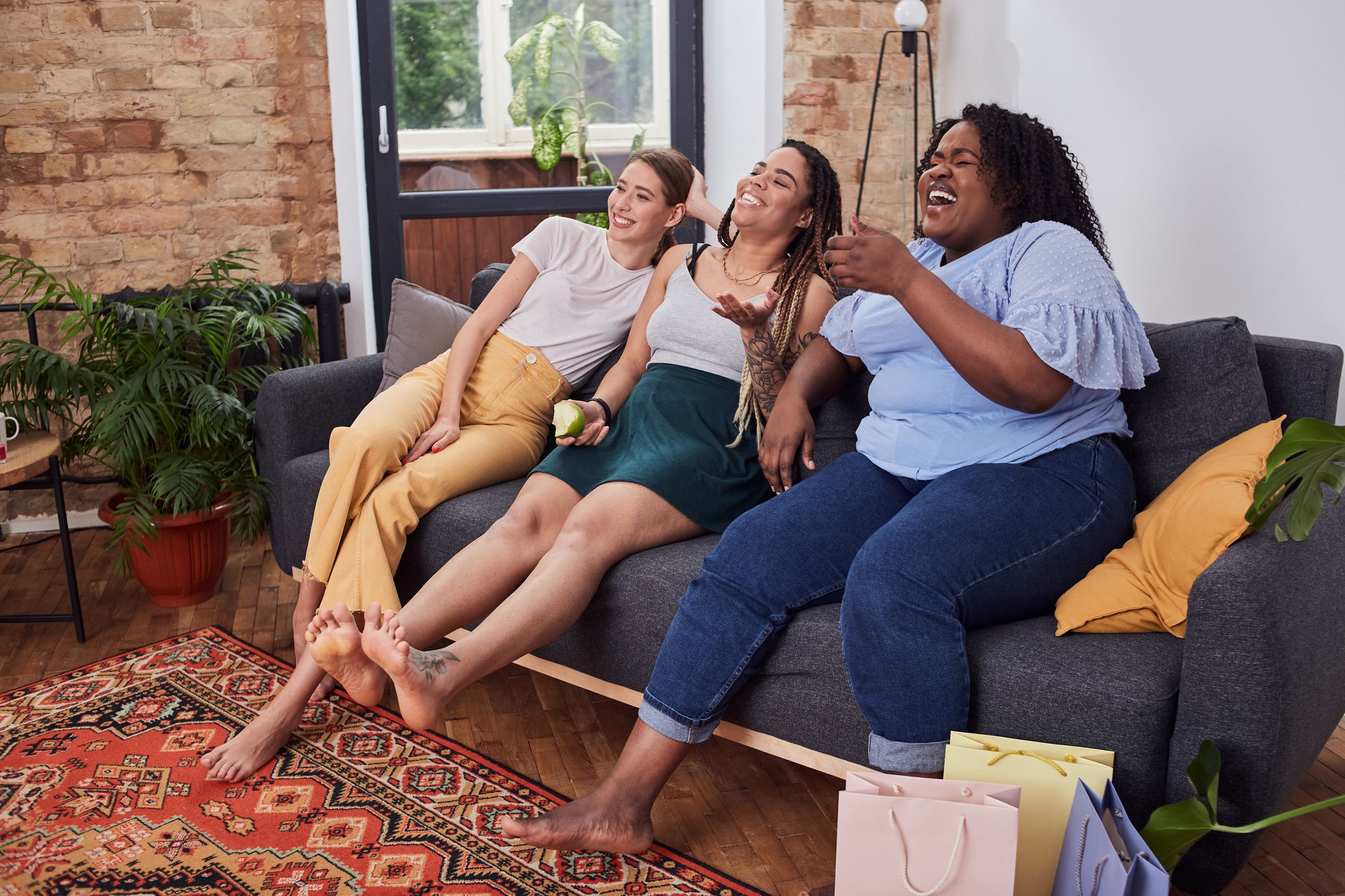 Joyful friends watching comedy movie together while resting on couch and laughing