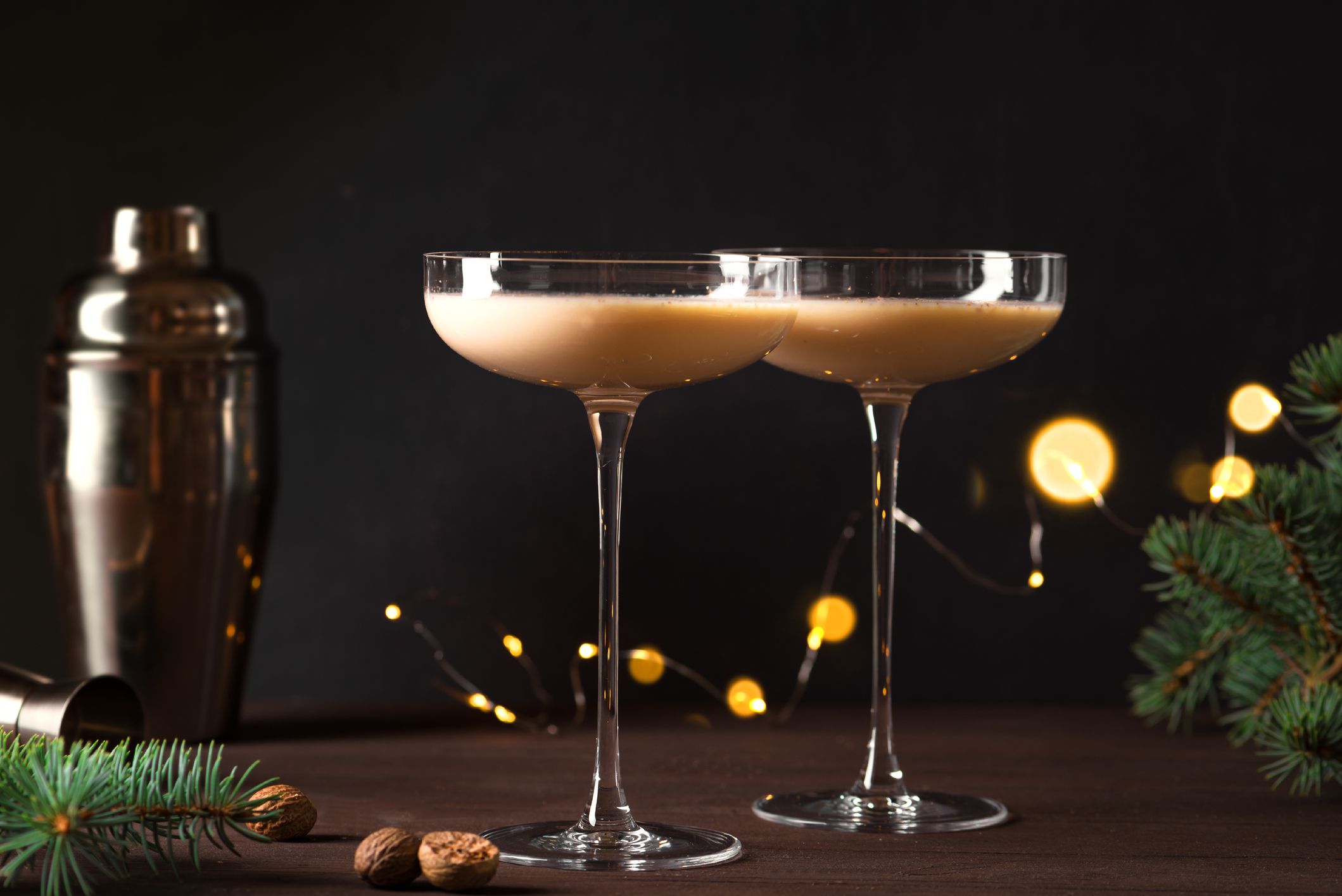 Christmas Brandy Alexander Cocktail on wooden table with lights and Christmas decor. Festive homemade cocktail drink for winter holidays.