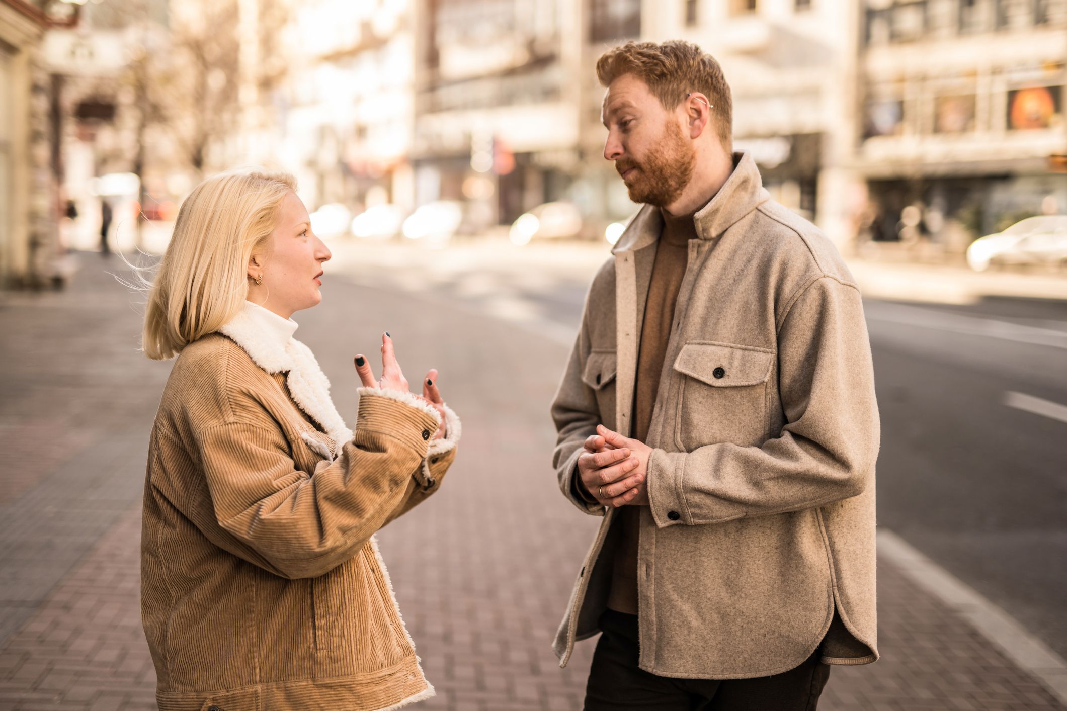 Young couple communicating on city street. Young woman talking with young man in the city. Two young people meeting each other on city street.
