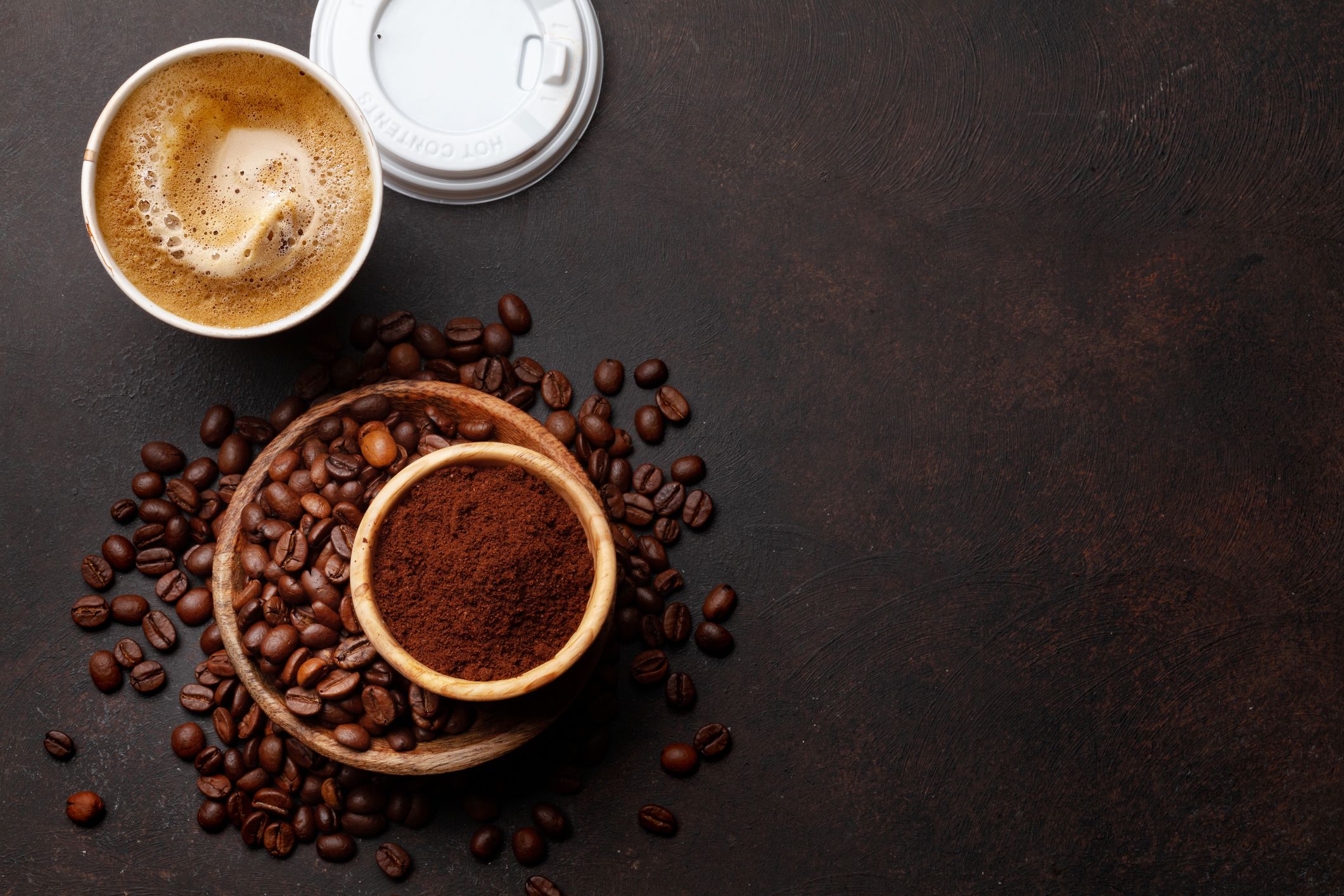 Fresh coffee in takeaway cup, roasted coffee beans and ground coffee. Top view flat lay