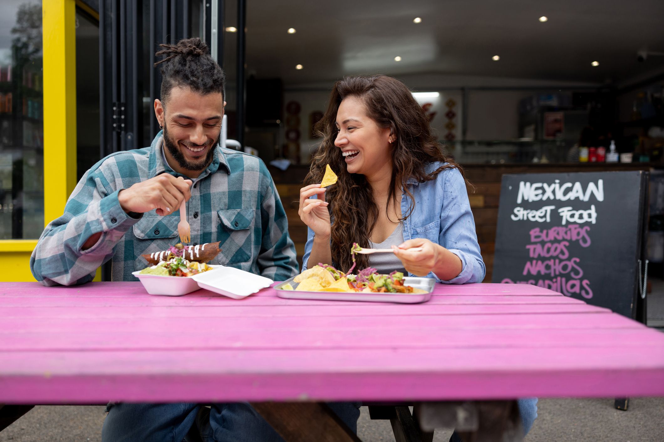 Loving couple looking happy eating tacos at a small Mexican restaurant â street food concepts