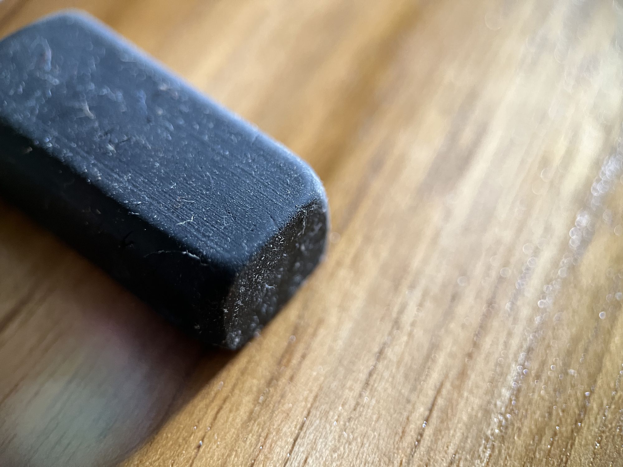 Selective focus view of black rubber eraser on wooden background. Macro photography.